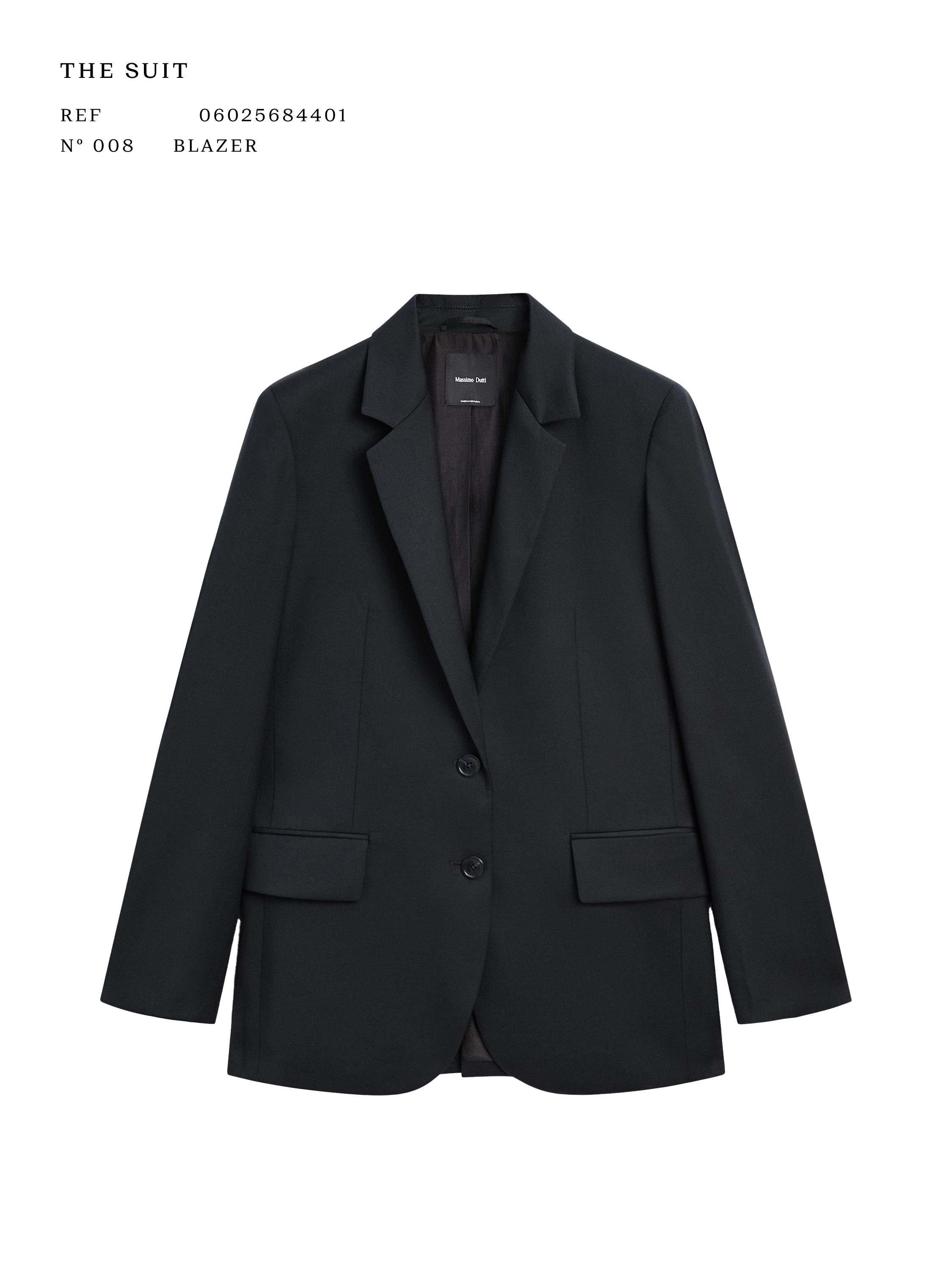 Vue frontale de blazer bleu marine avec revers classiques, deux boutons et poches à rabat. Texte visible : "THE SUIT", "RÉF 06025684401".