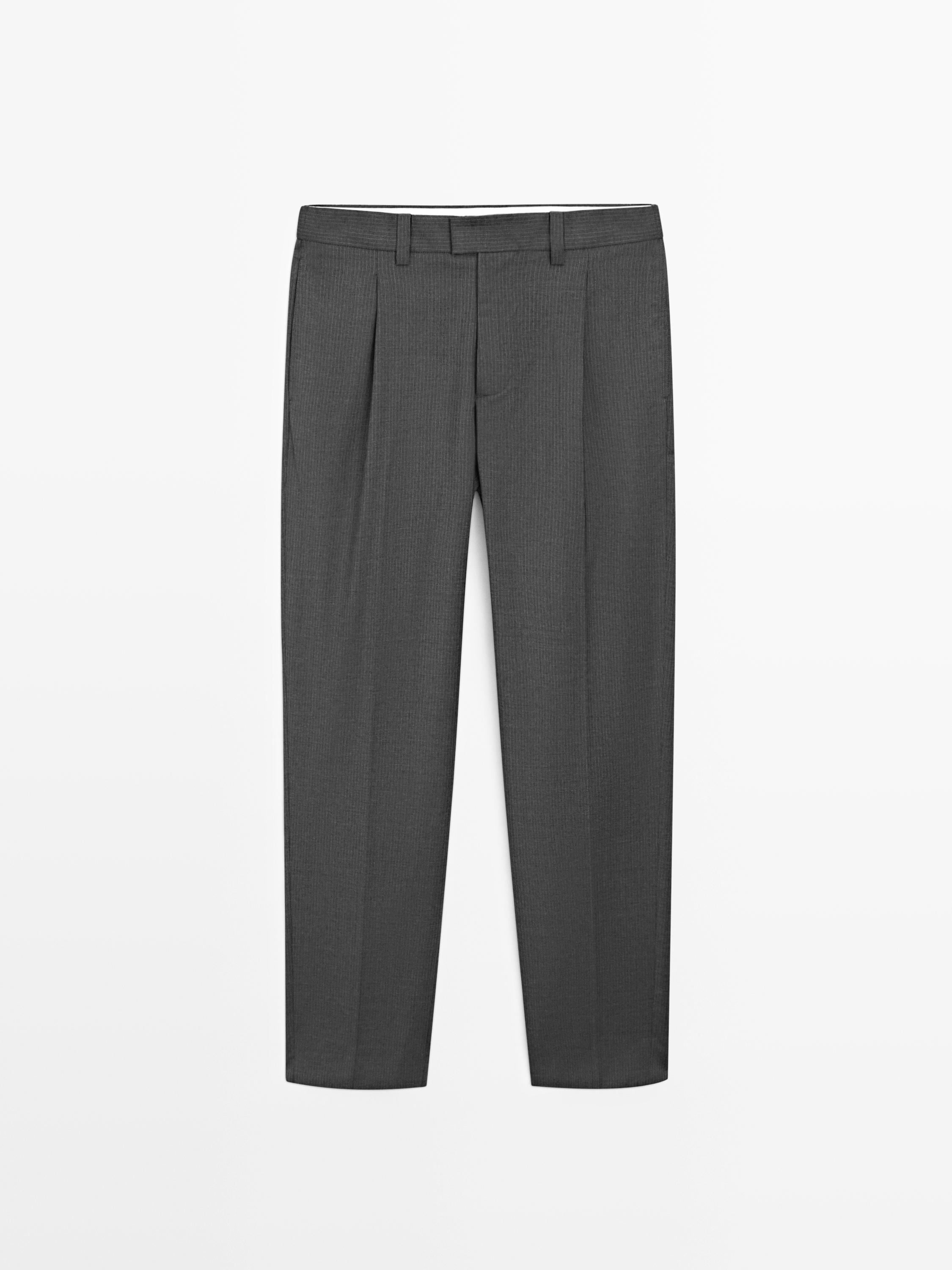 Eestvaade hallidele pükstele voltide, küljetaskute ja vööaasadega.