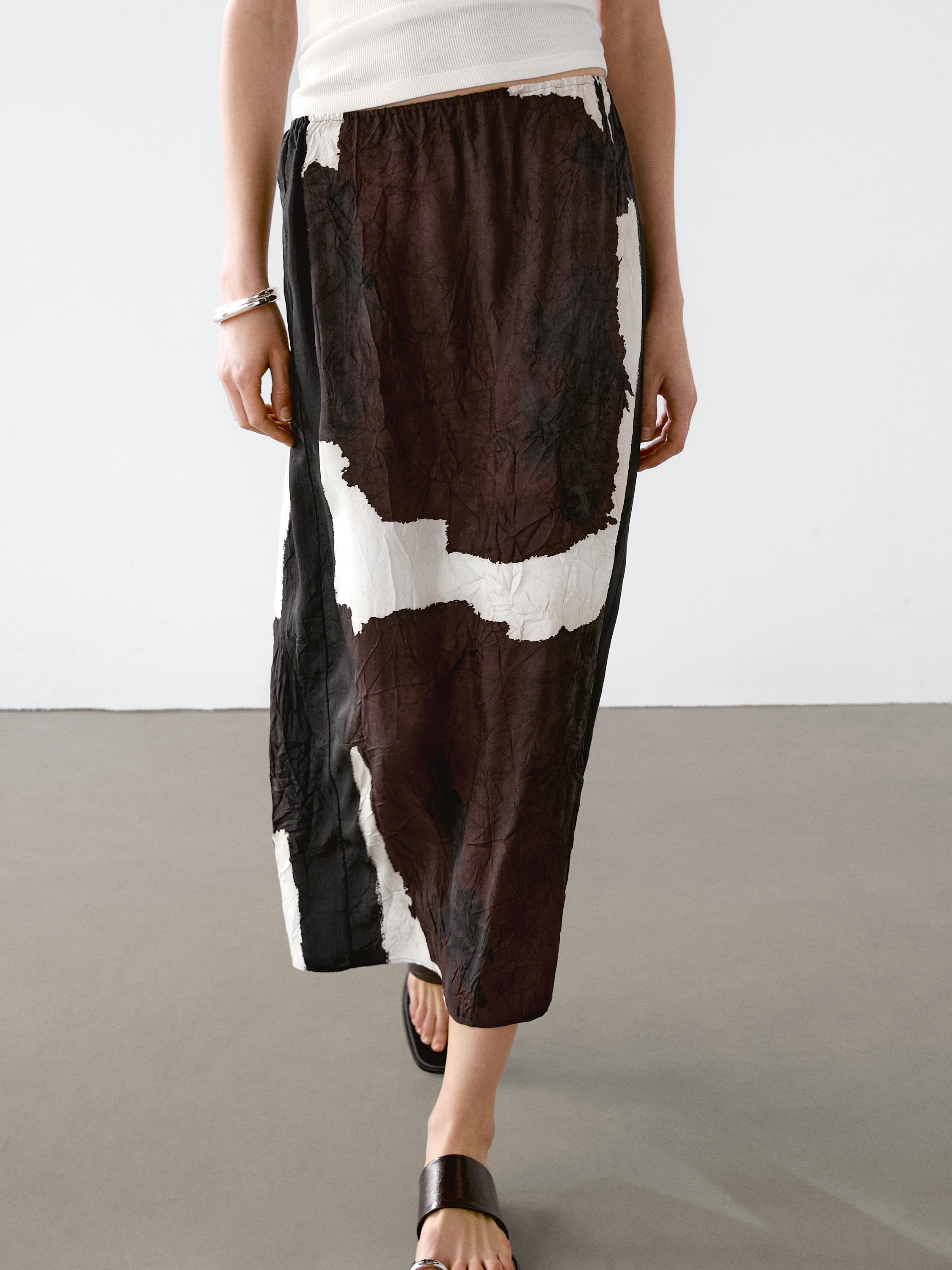 Ensemble jupe midi marron et blanche imprimée avec des sandales noires.