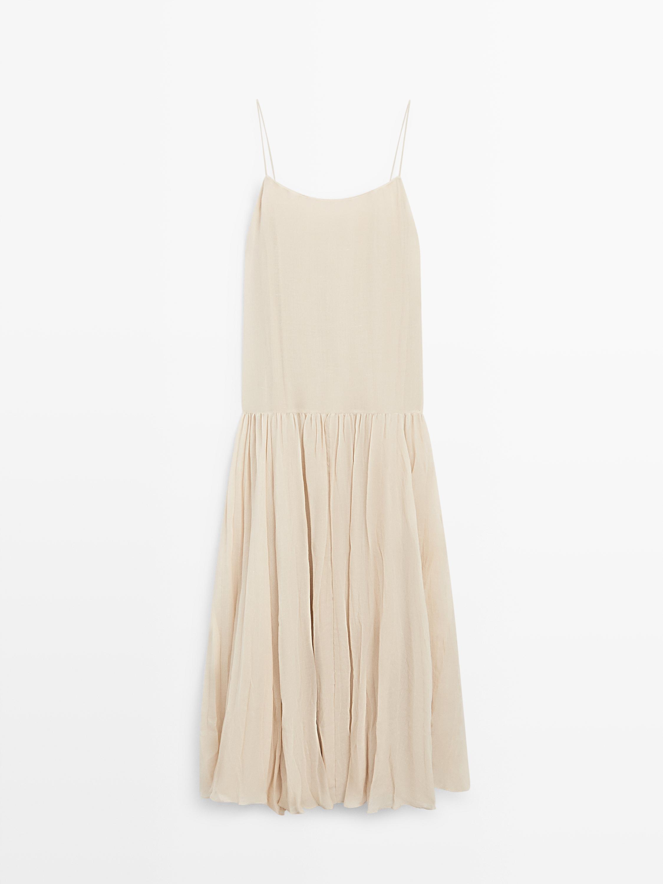 Vue de face d'une robe écru avec de fines bretelles et une jupe plissée.