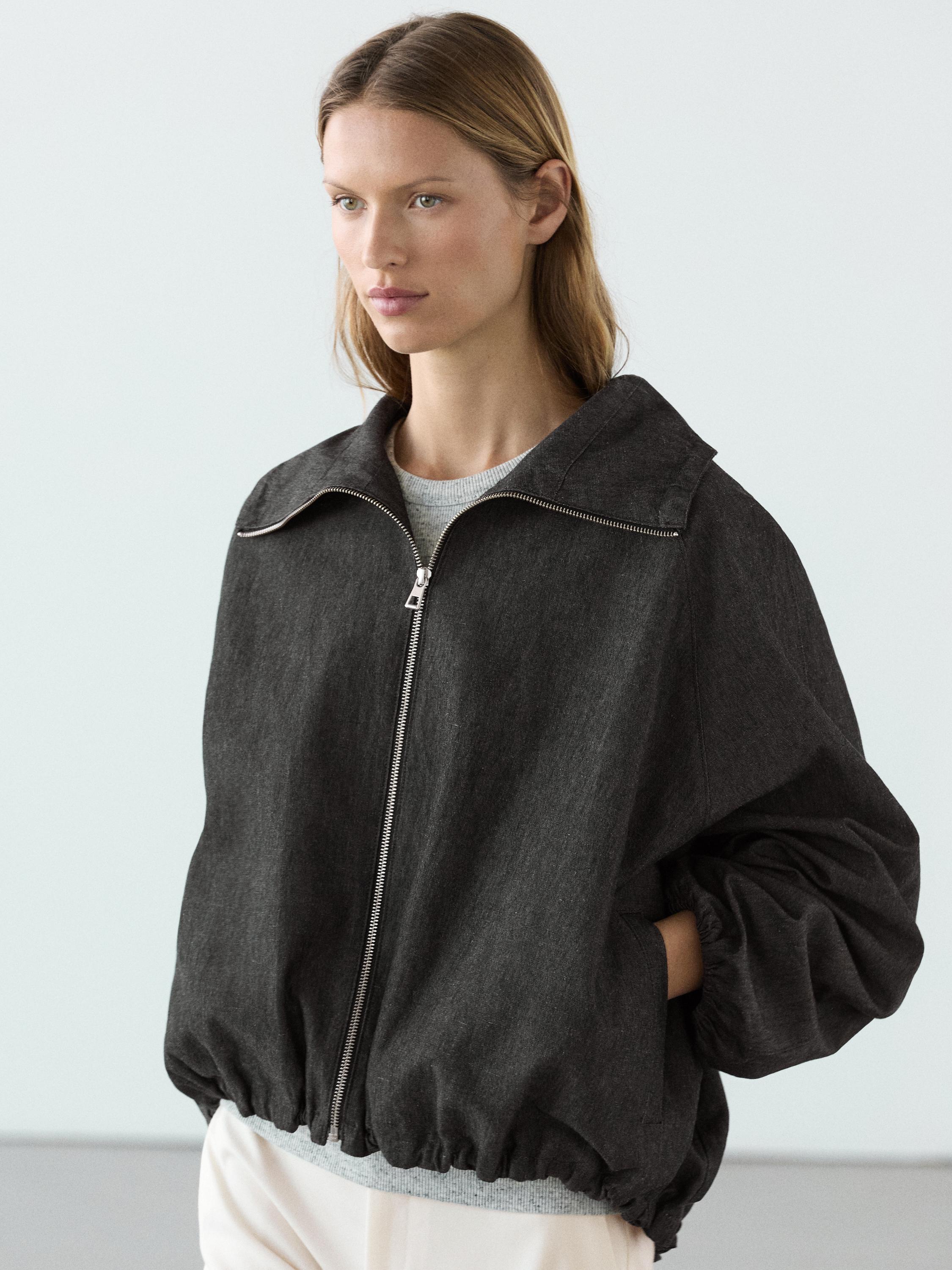 Halftotaal van een grijsblauwe bomberjack met ritssluiting aan de voorkant en zijzakken.