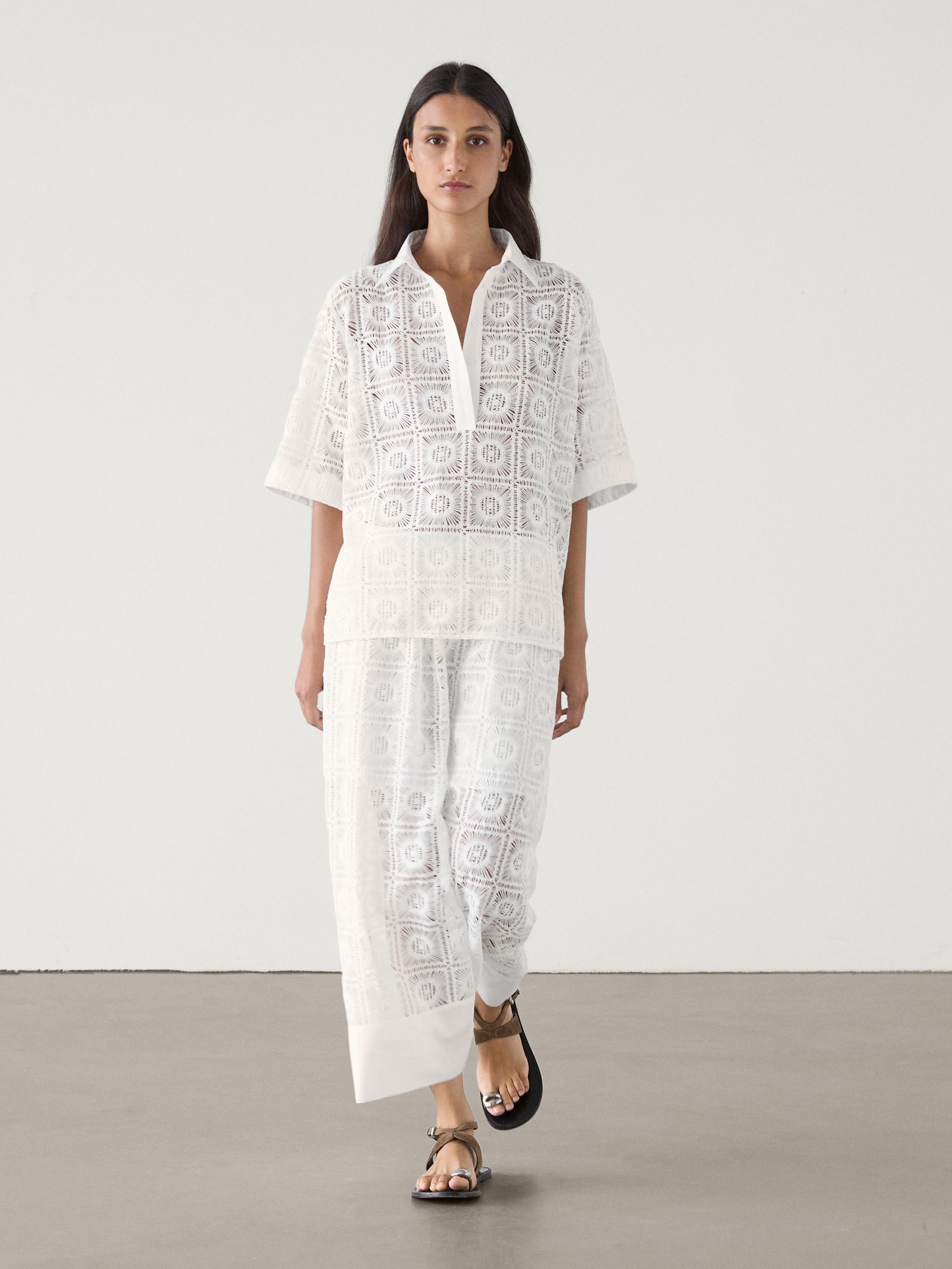 Ensemble blouse et pantalon blanc avec dentelle géométrique, blouse à manches courtes et col en V.