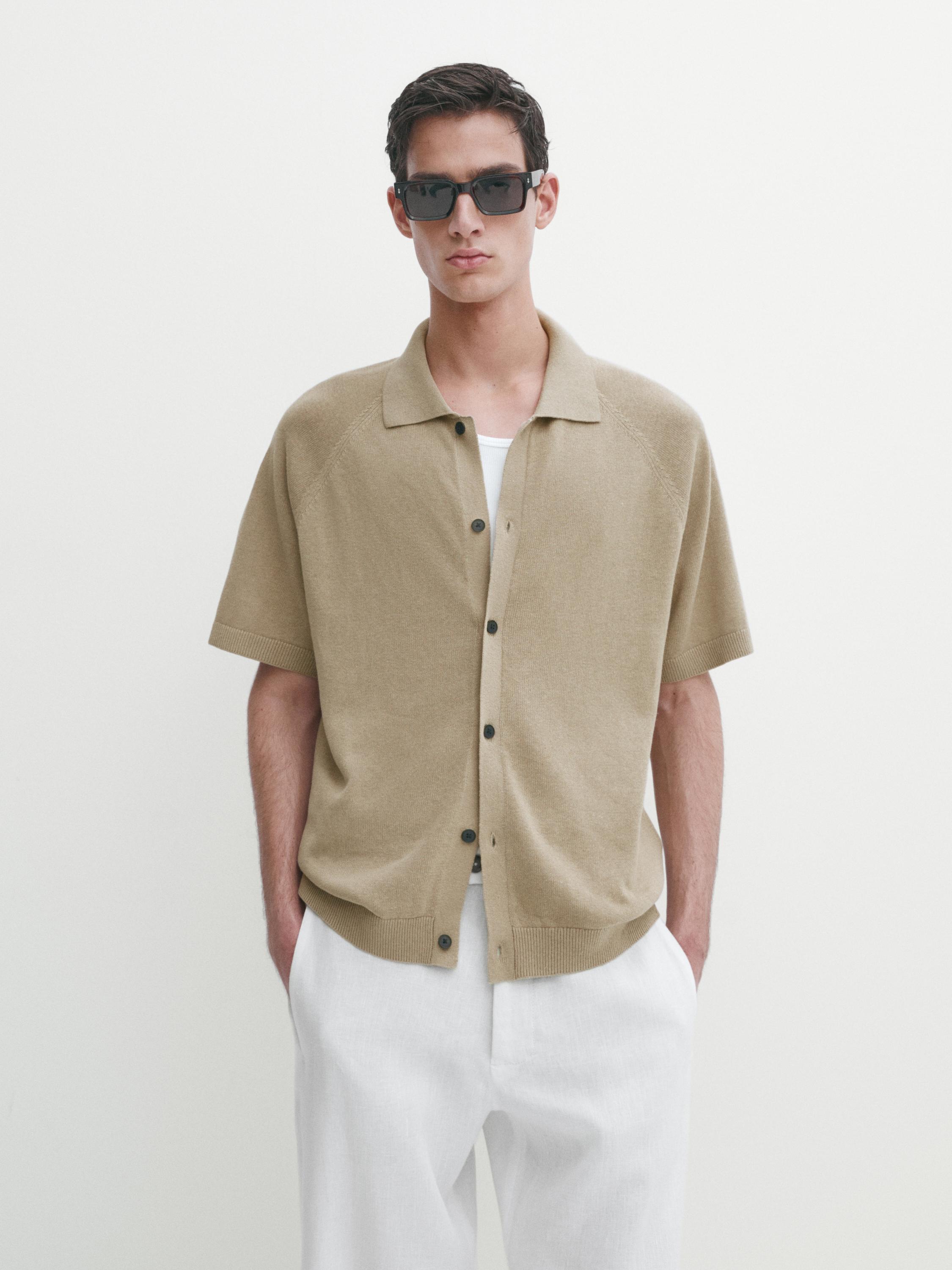 Ensemble composé d'une chemise beige à manches courtes boutonnée et d'un pantalon blanc.