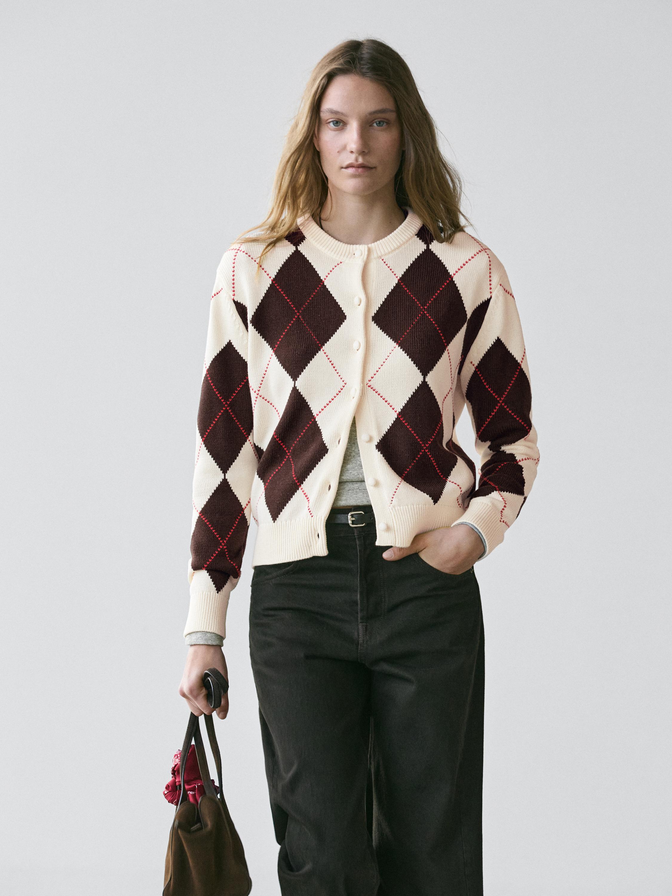 Ecru cardigan set with brown and red argyle, front buttons, dark pants, and brown bag.
