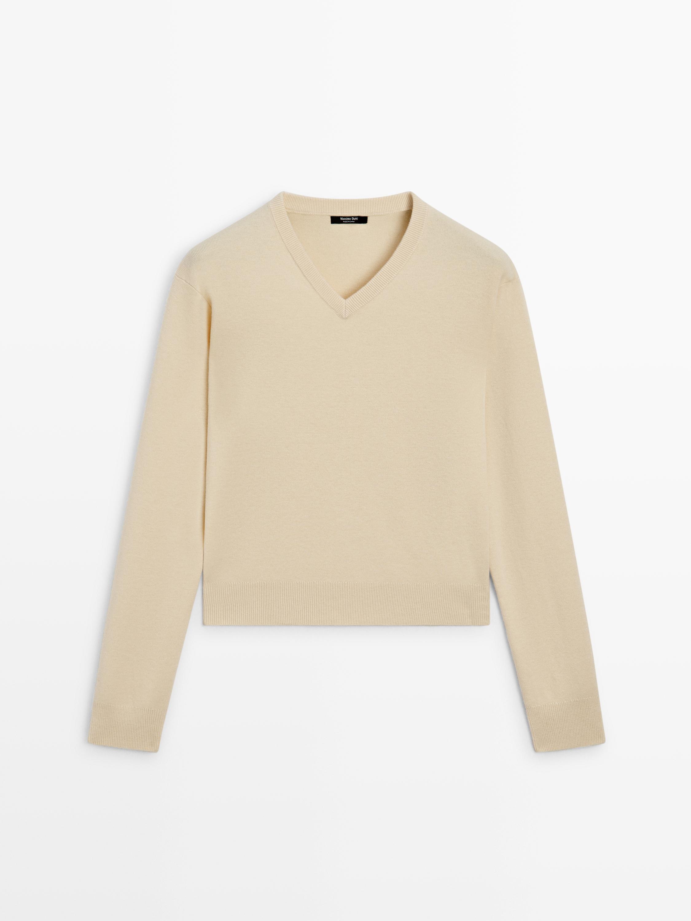 Front view of a vanilla knit V-neck sweater with long sleeves.