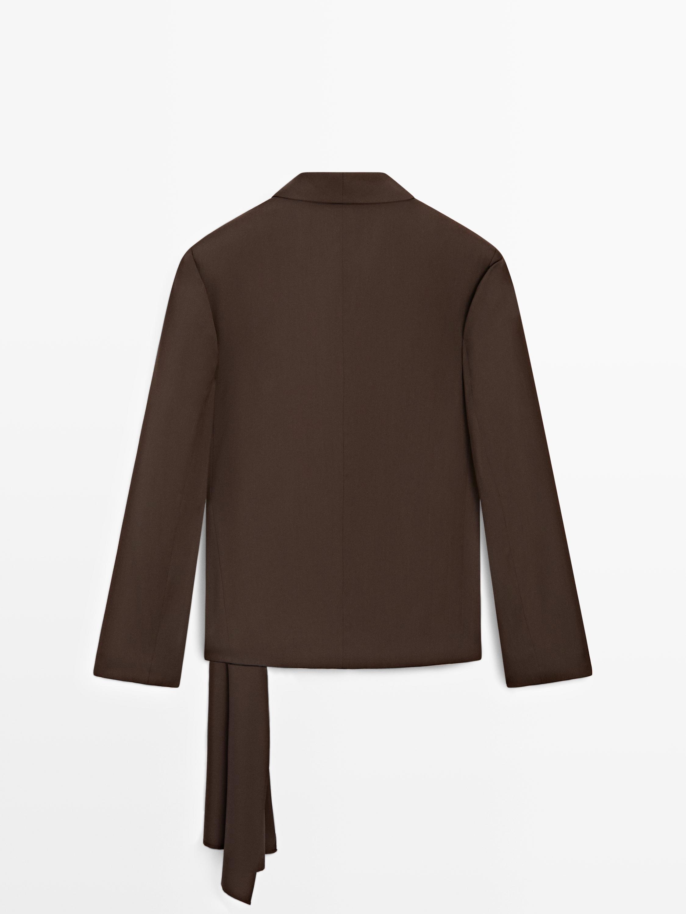 Πίσω όψη σοκολατί σακακιού με λεπτομέρεια δέσης στο κάτω μέρος.