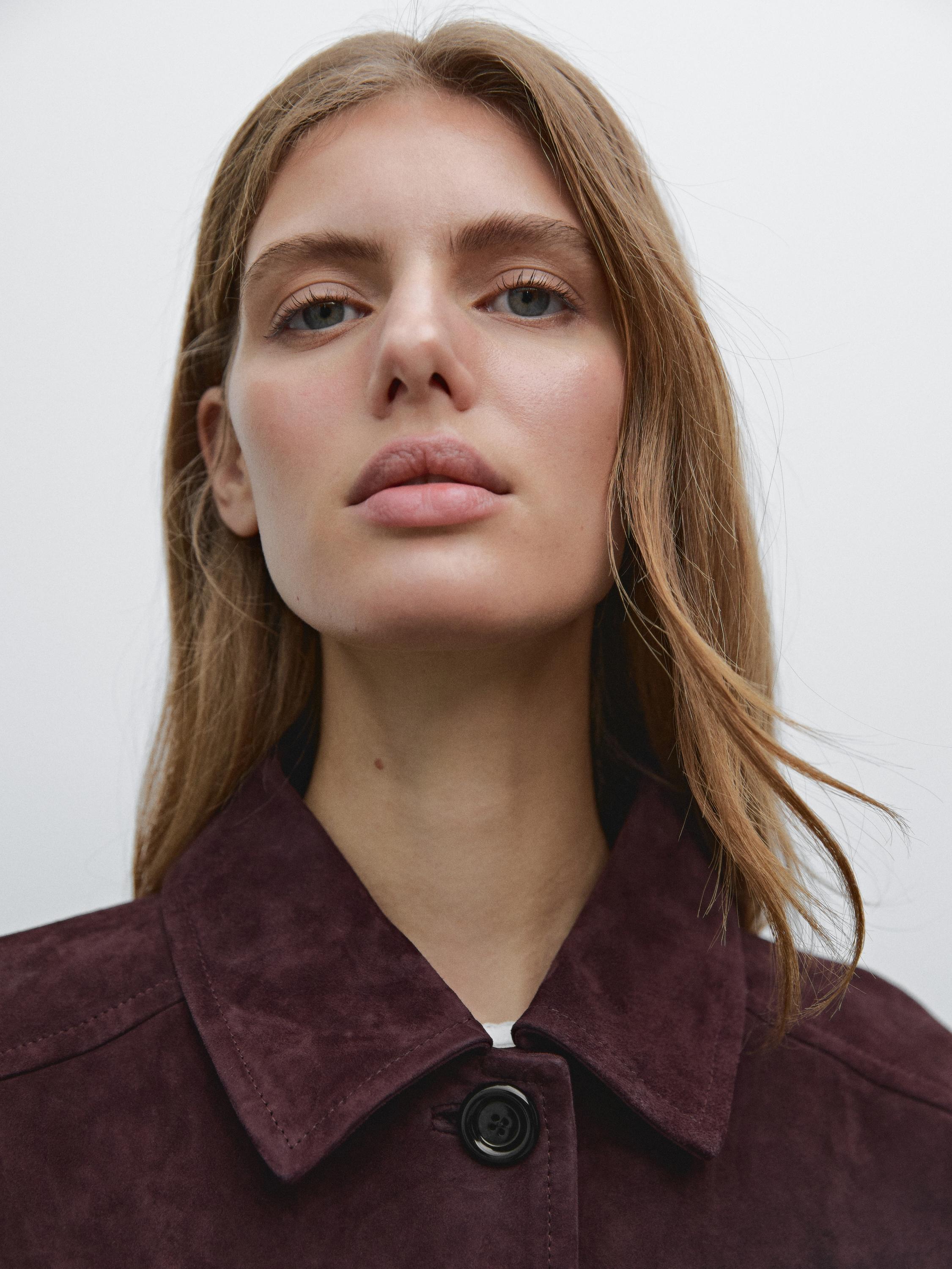 Détail du col d'un manteau bordeaux avec bouton noir.