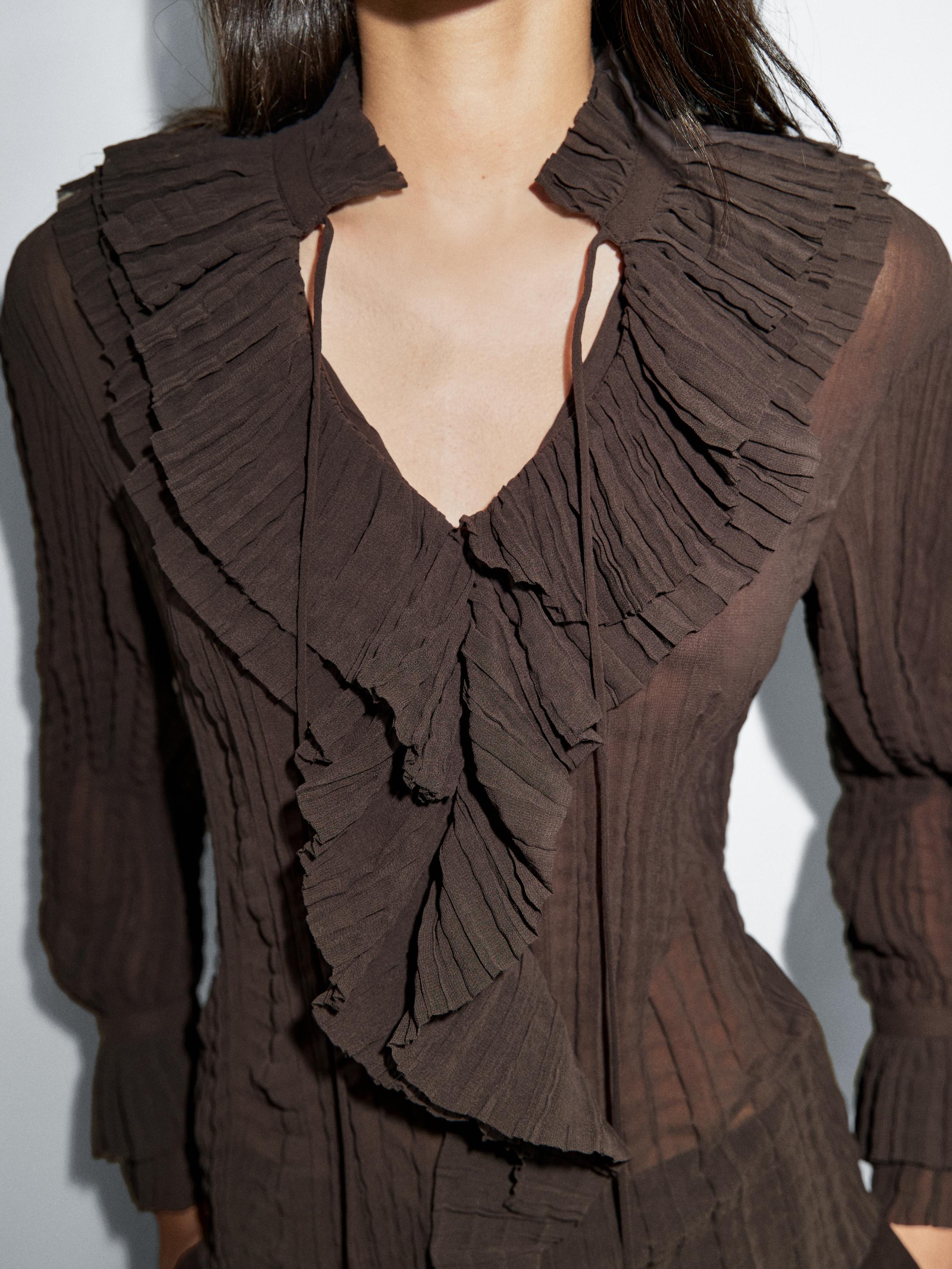 "Plan moyen d'une chemise marron avec des plis et des volants au niveau du col et de la poitrine."