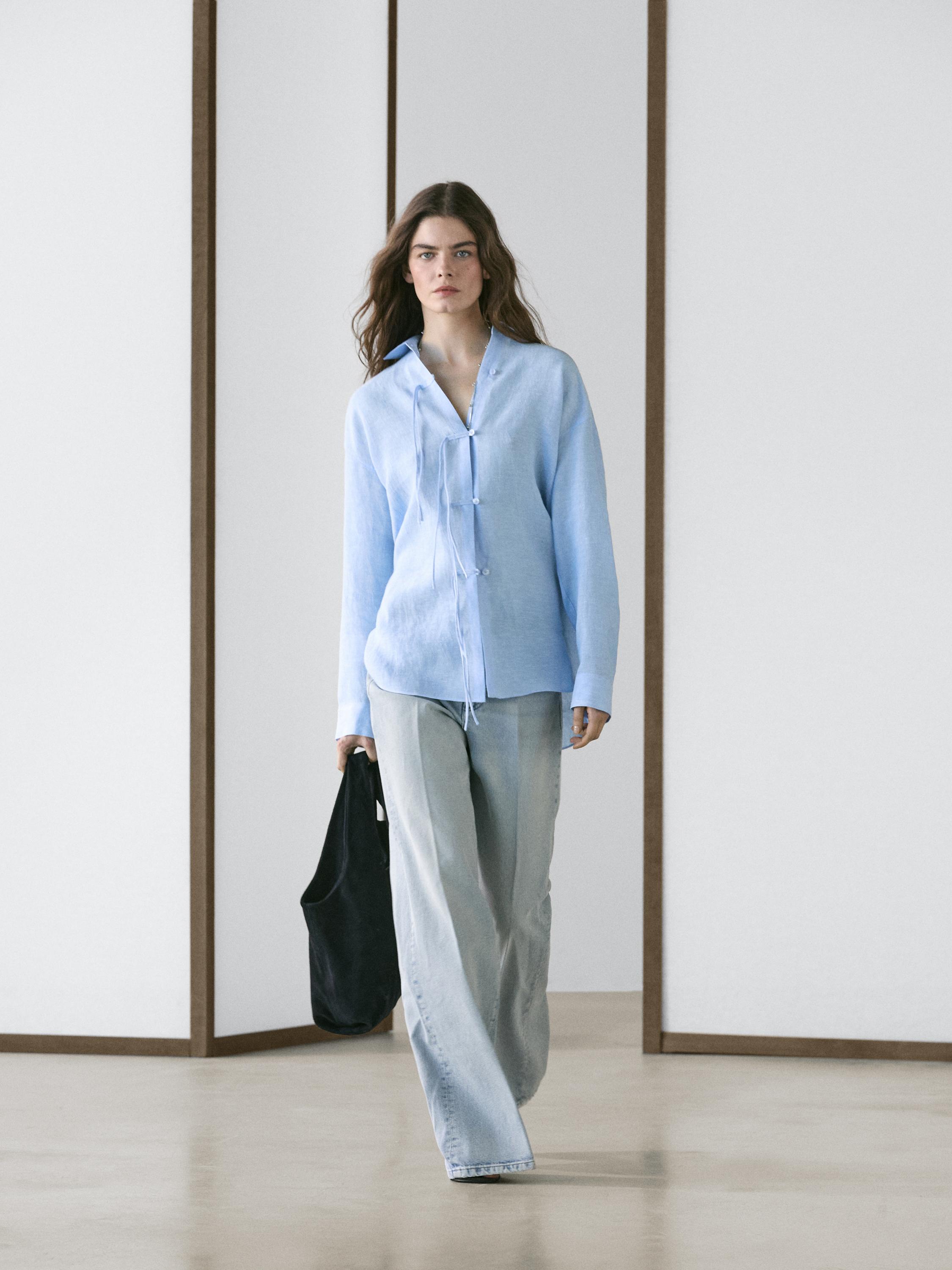 Σετ από γαλάζιο φαρδύ πουκάμισο με κορδόνια στο λαιμό και ανοιχτόχρωμο φαρδύ τζιν παντελόνι.