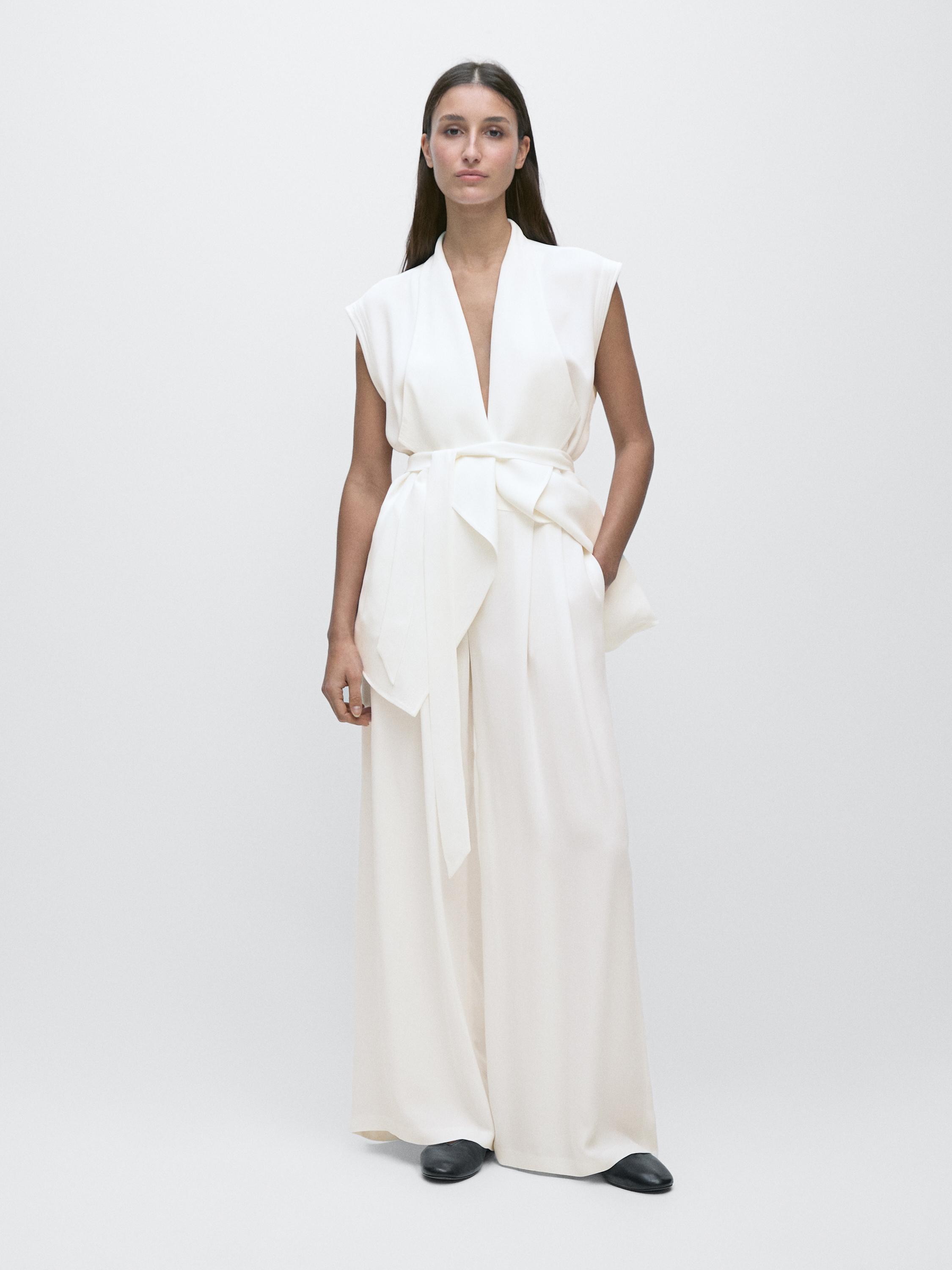 Set rompi tanpa lengan dan celana putih tulang dengan sabuk tali dan saku samping.