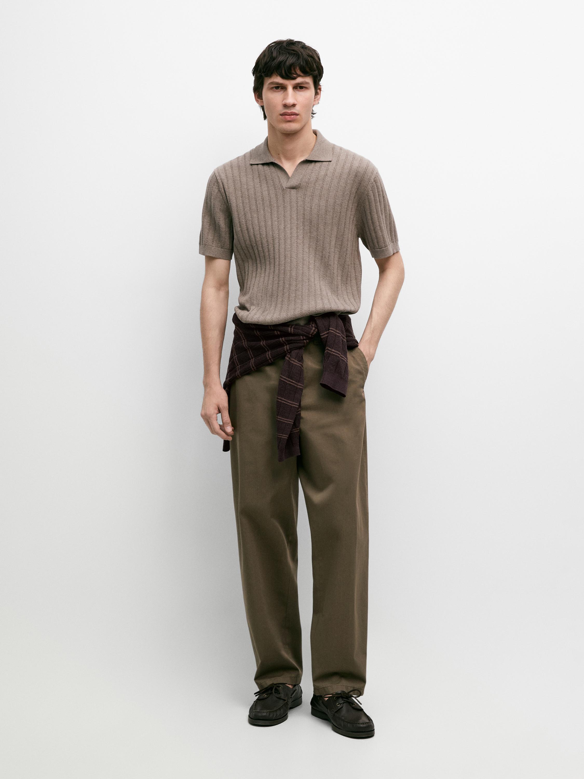Conjunto de jersey polo visón de punto trenzado, pantalones marrones y camisa a cuadros atada a la cintura.