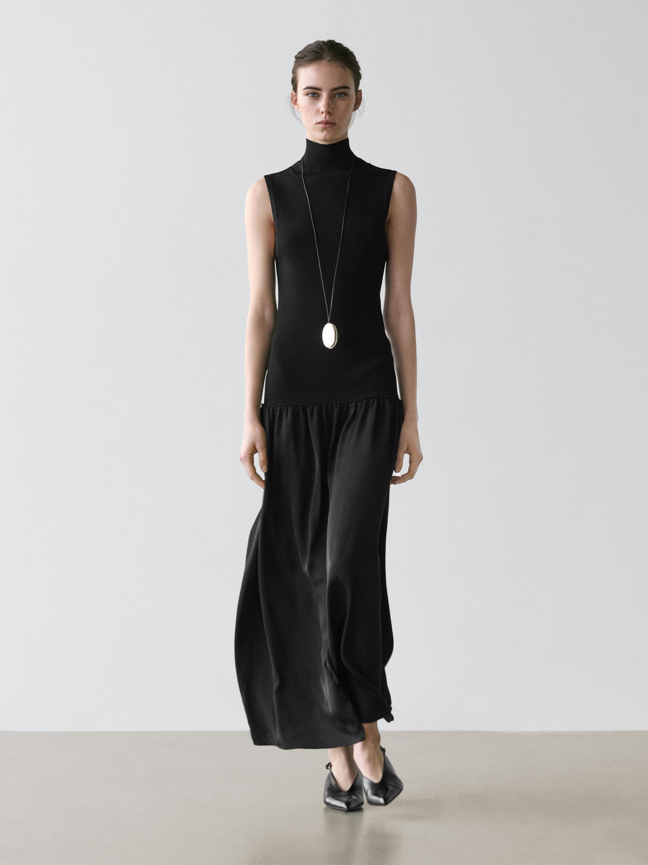Sleeveless black dress set with a turtleneck and a flowing long skirt.