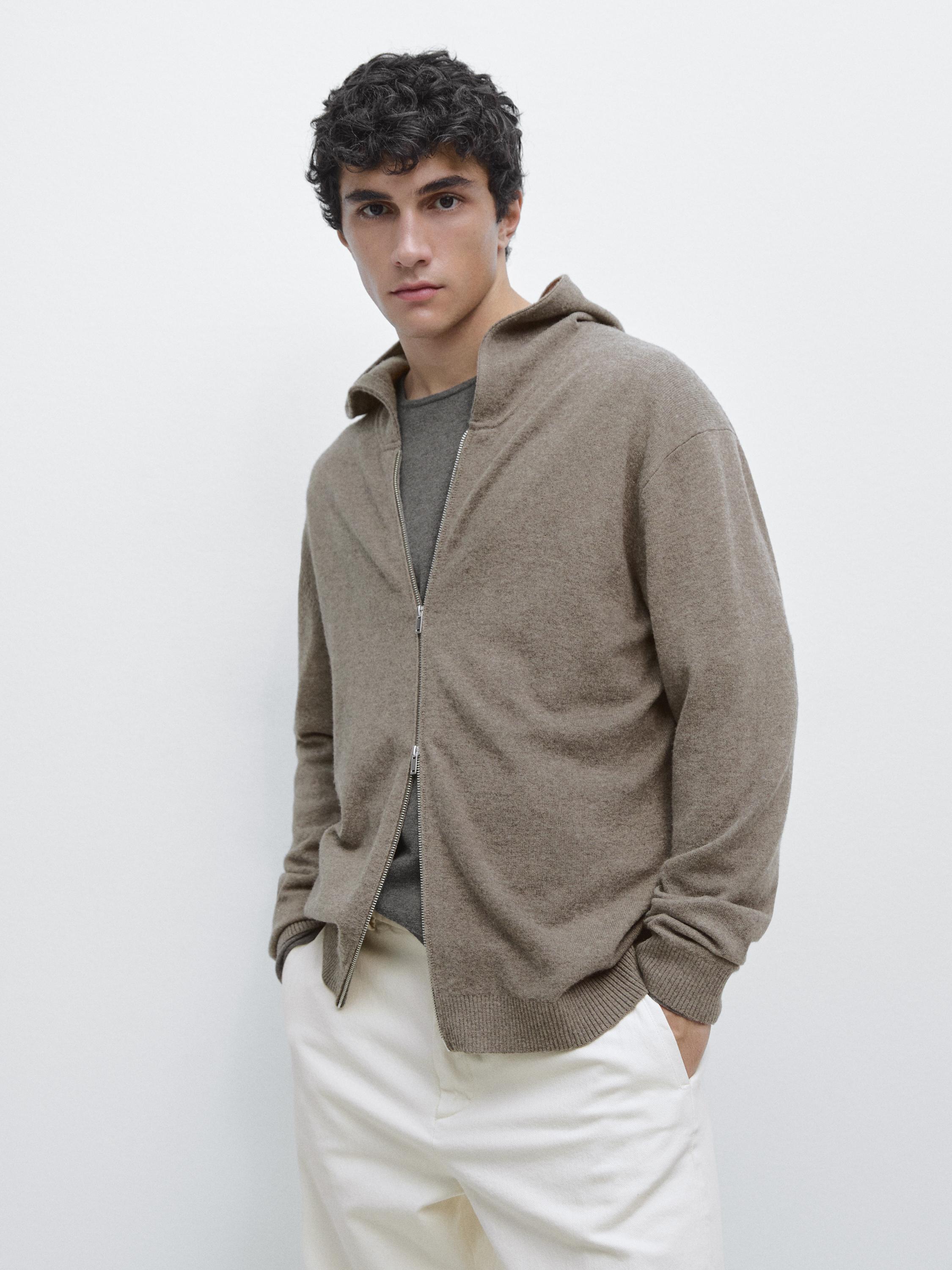 Ensemble cardigan kaki foncé à capuche zippé, sur t-shirt gris et pantalon clair.