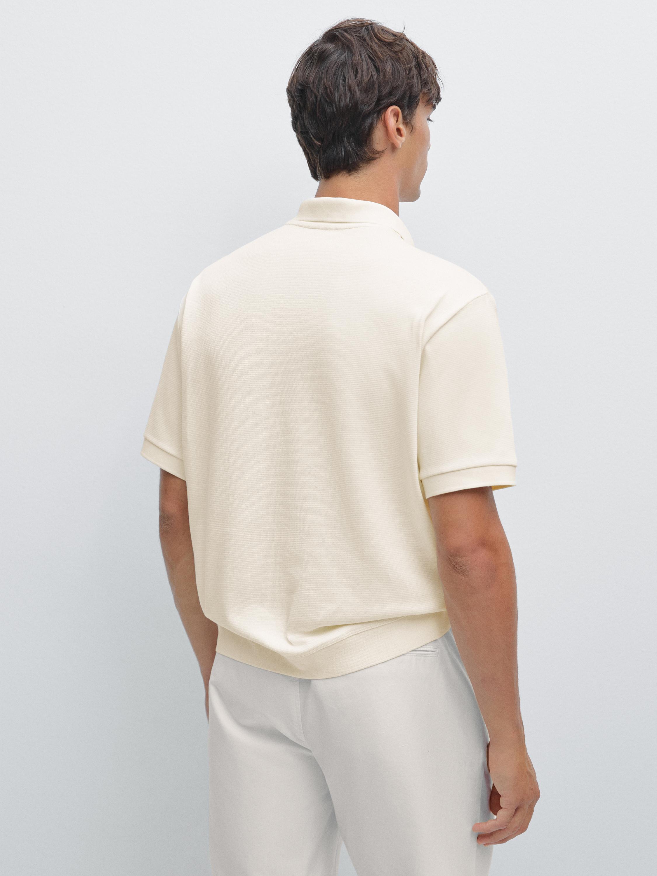 Ensemble de polo beige à manches courtes à col classique et pantalon blanc.