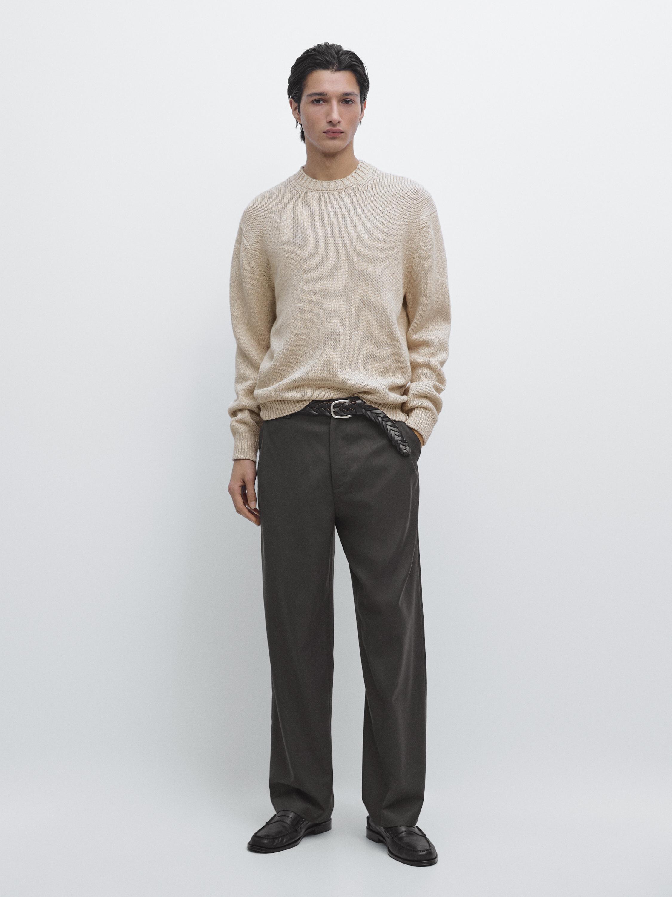 Ensemble de pull beige en maille à col rond et pantalon foncé coupe droite.