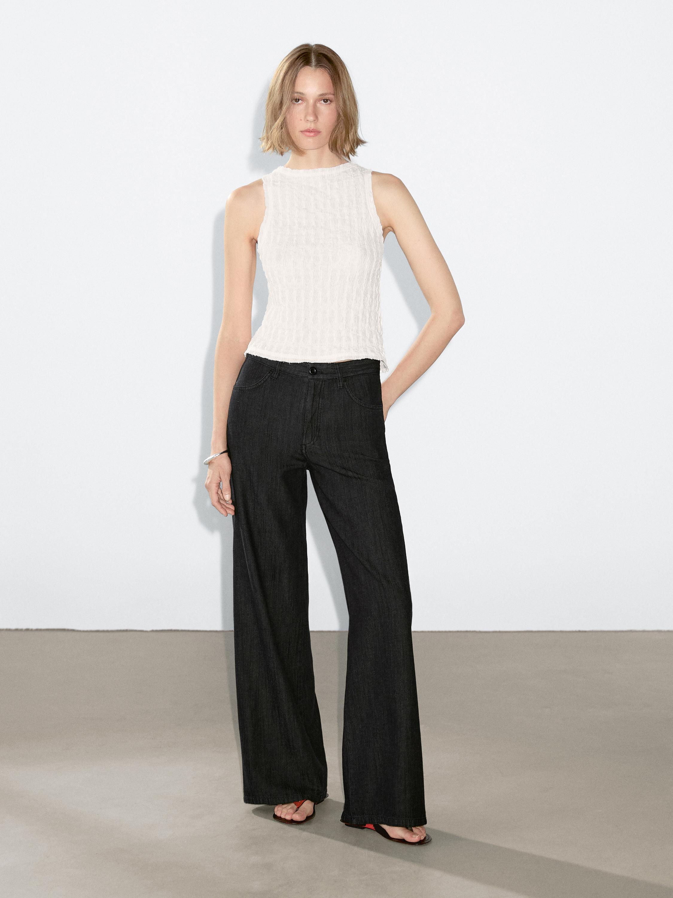 Ensemble composé d'un débardeur blanc et d'un jean ample gris foncé avec poches latérales.