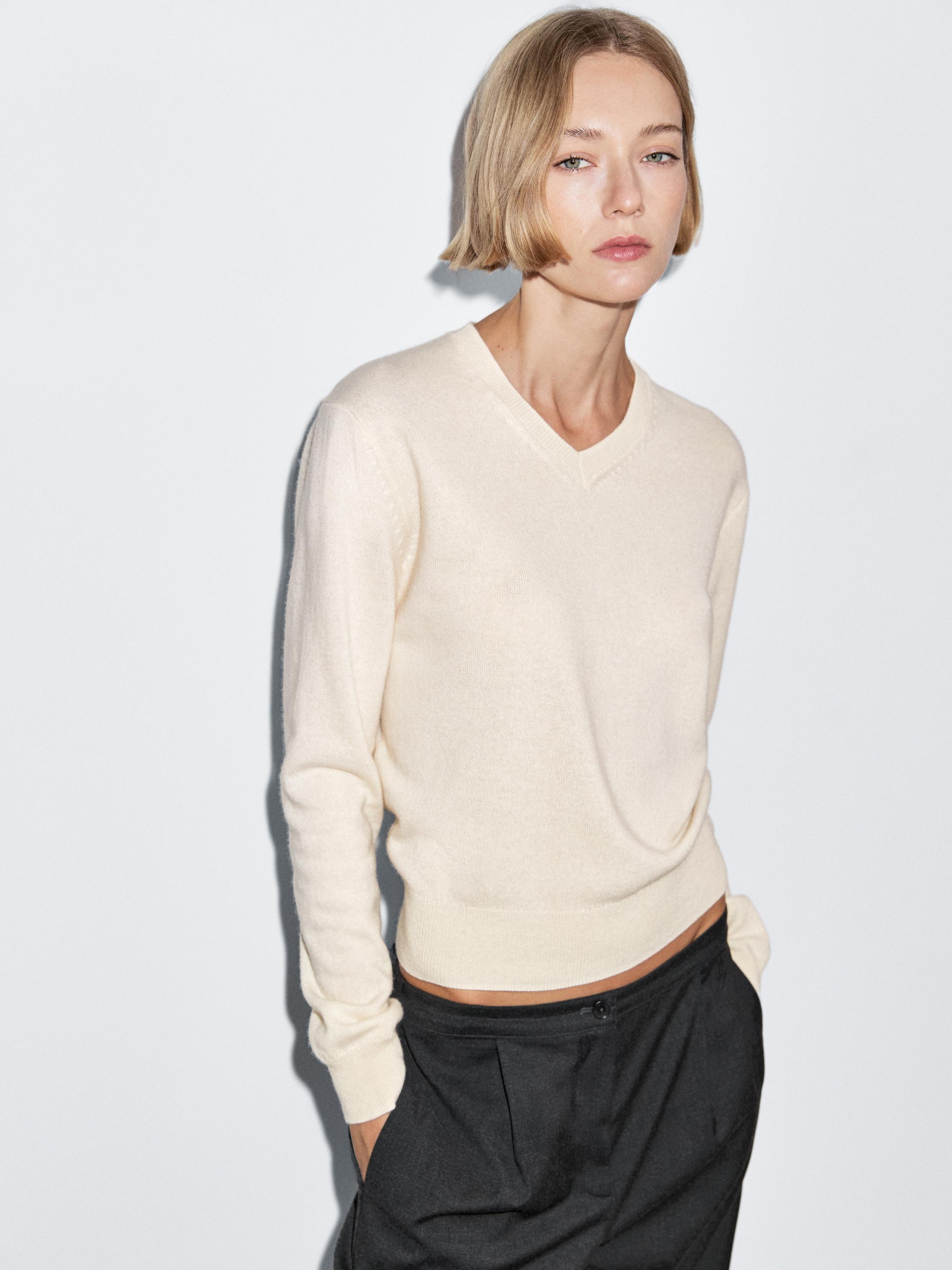 Beige V-neck sweater and black pants set.