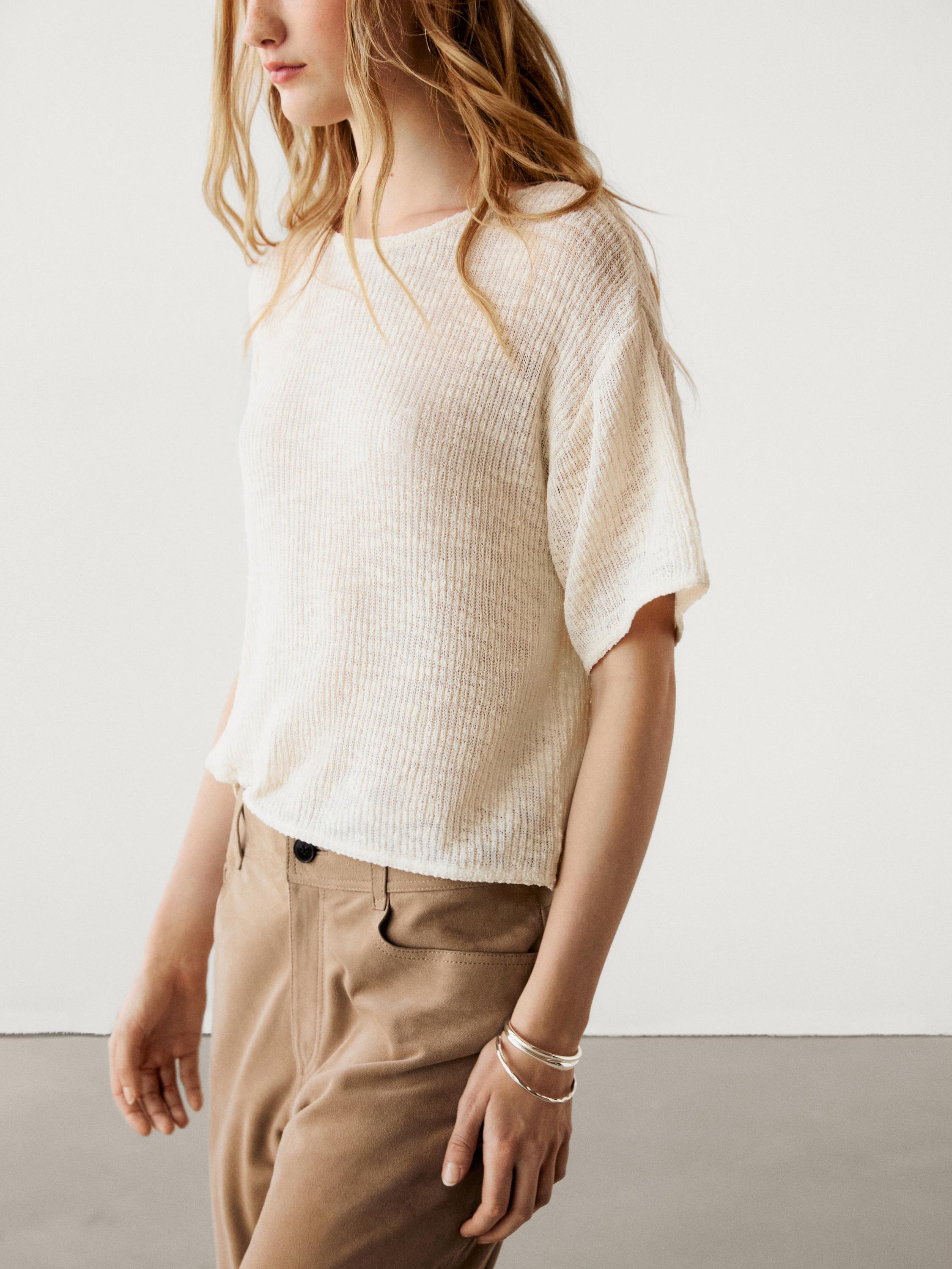 Gros plan sur un t-shirt beige à manches courtes et un pantalon beige avec des poches latérales.