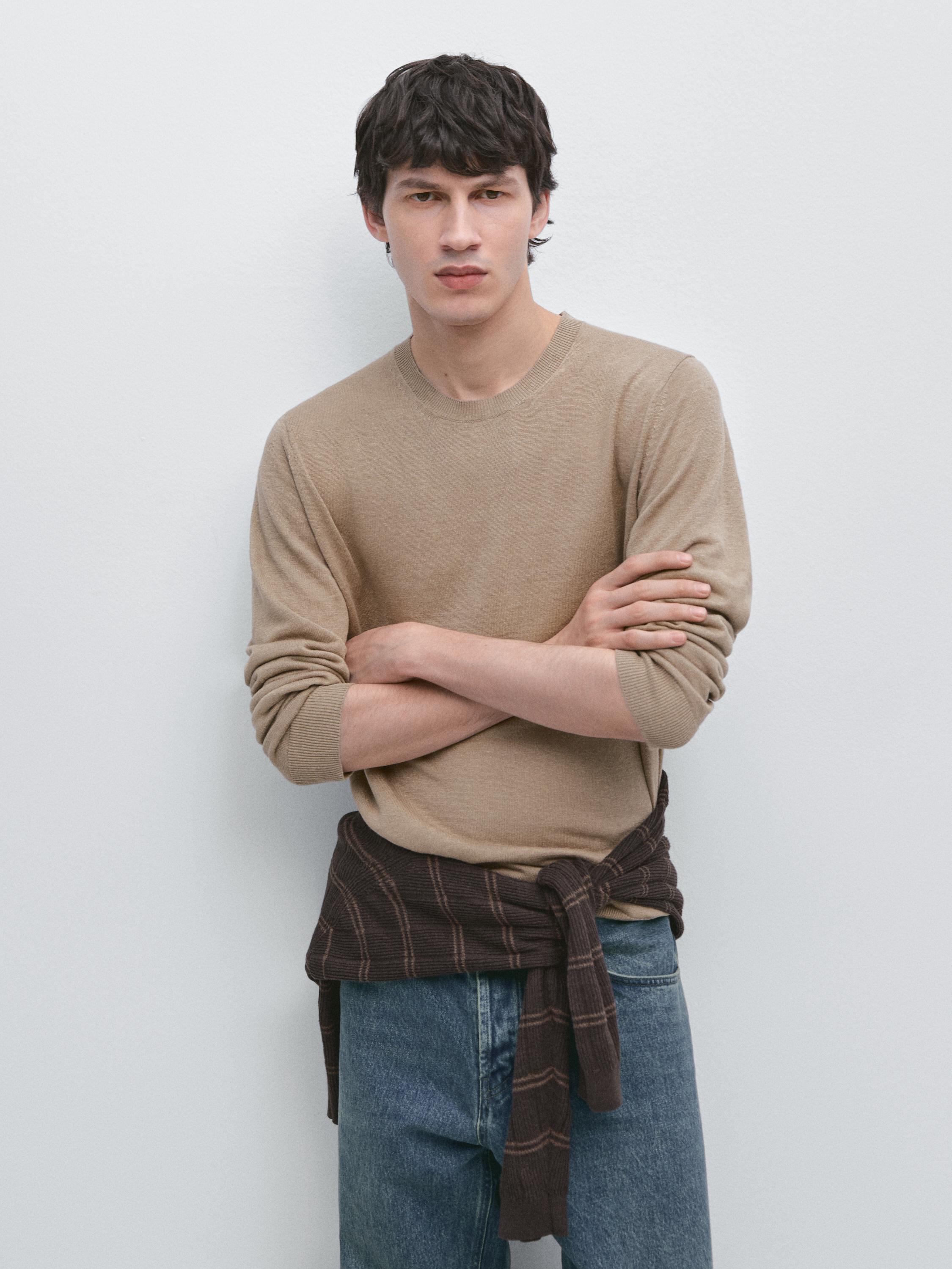 Plano medio de xersei amarelo claro de punto con colo redondo, mangas longas e corte recto.