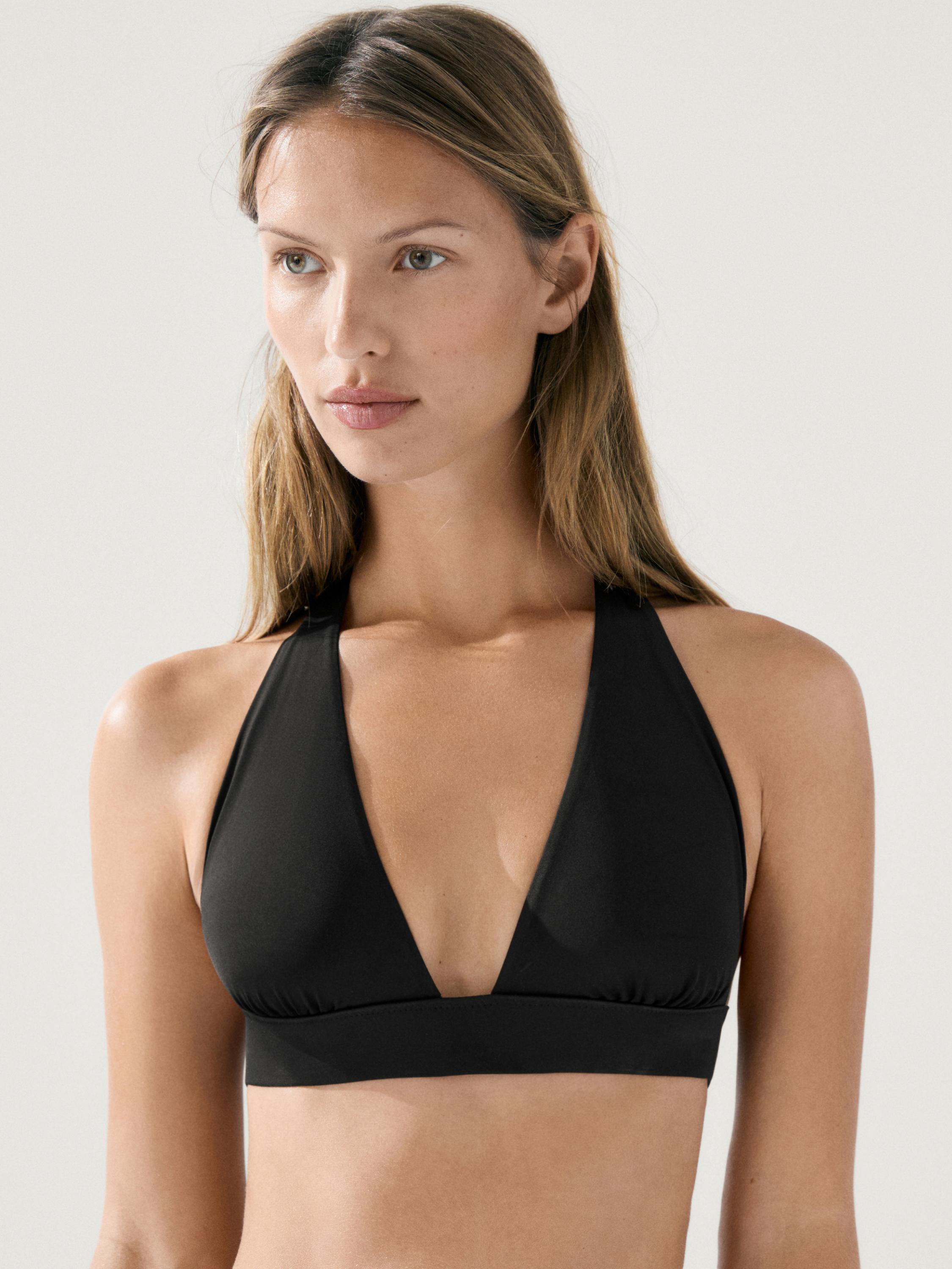 "Plano medio de top de bikini negro con escote en V profundo y tirantes anchos."