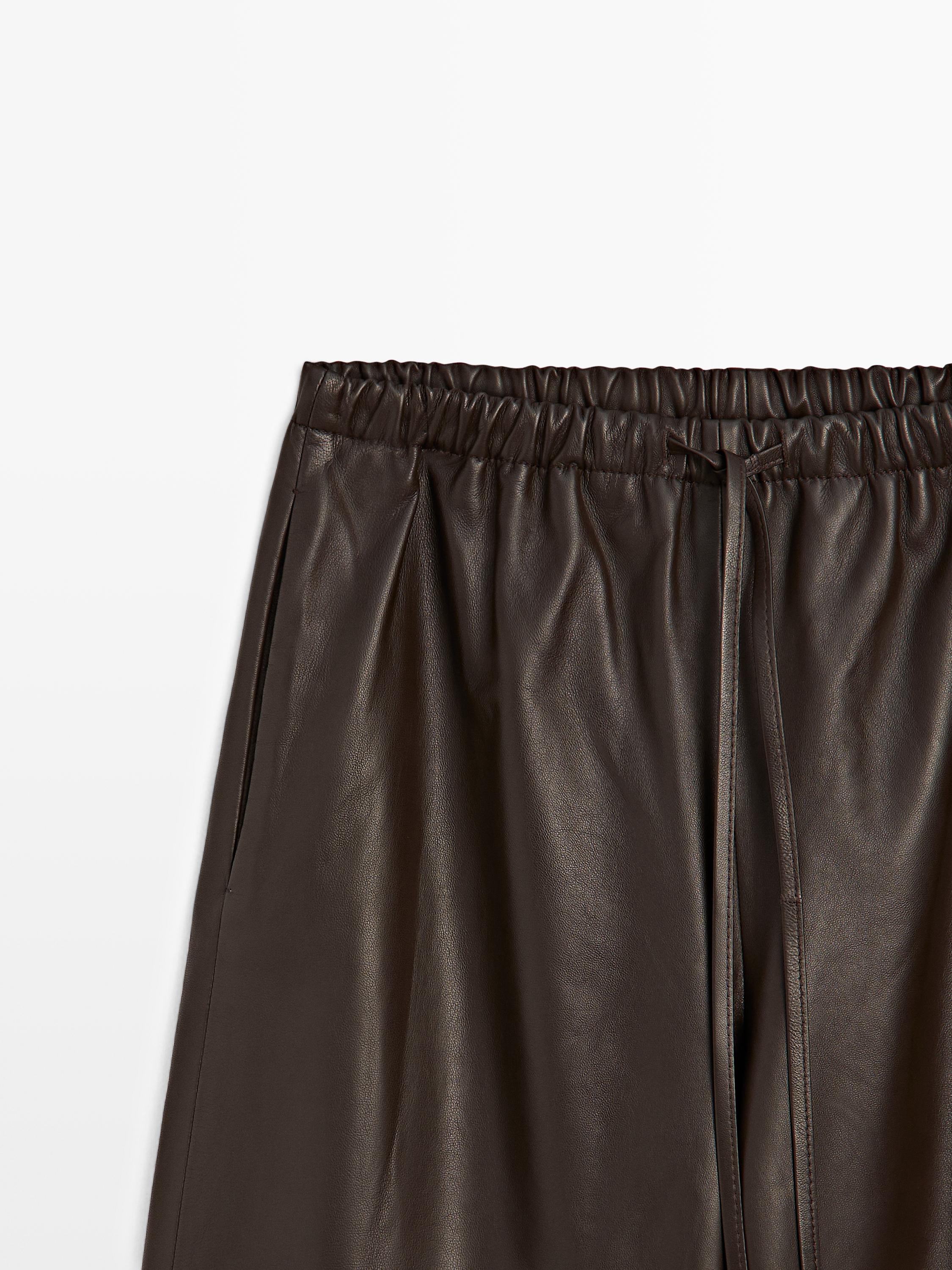 "Plano medio de pantalón marrón con cintura elástica y cordón, bolsillos laterales visibles."