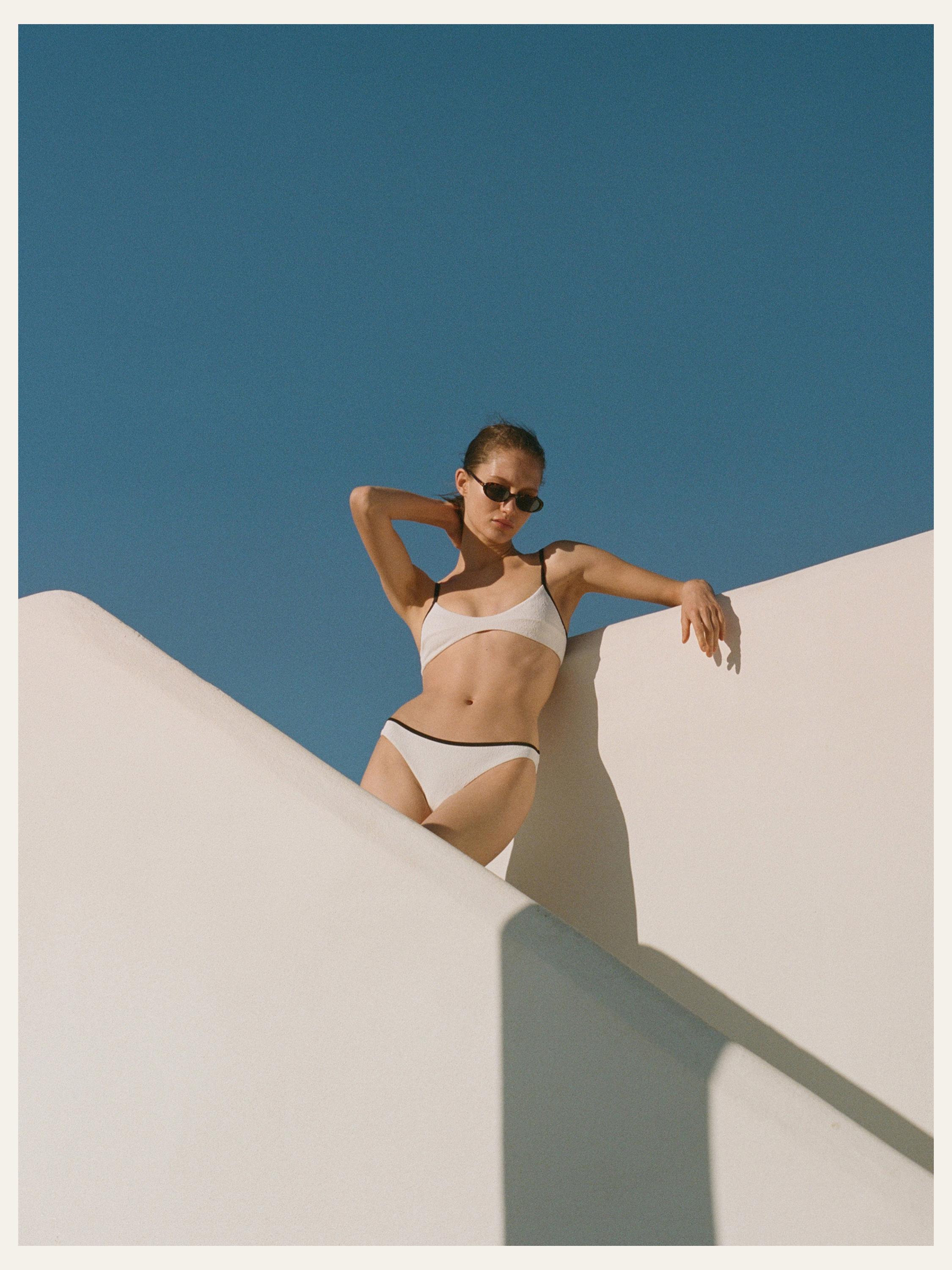 Siyah biyeli, ince askılı, klasik kesim külotlu beyaz bikini takımı.