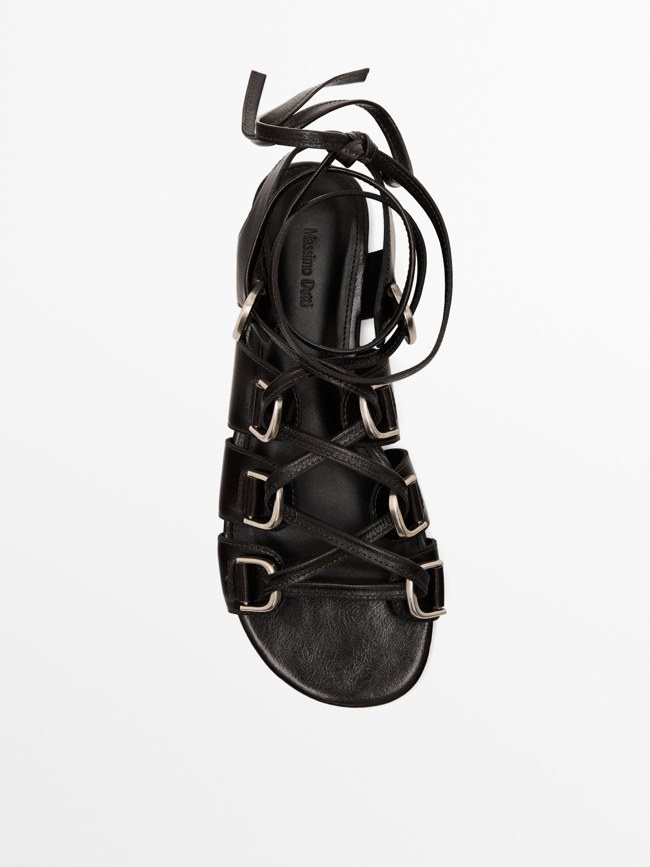 منظر علوي لصندل أسود بسيور متقاطعة وإبزيم معدني