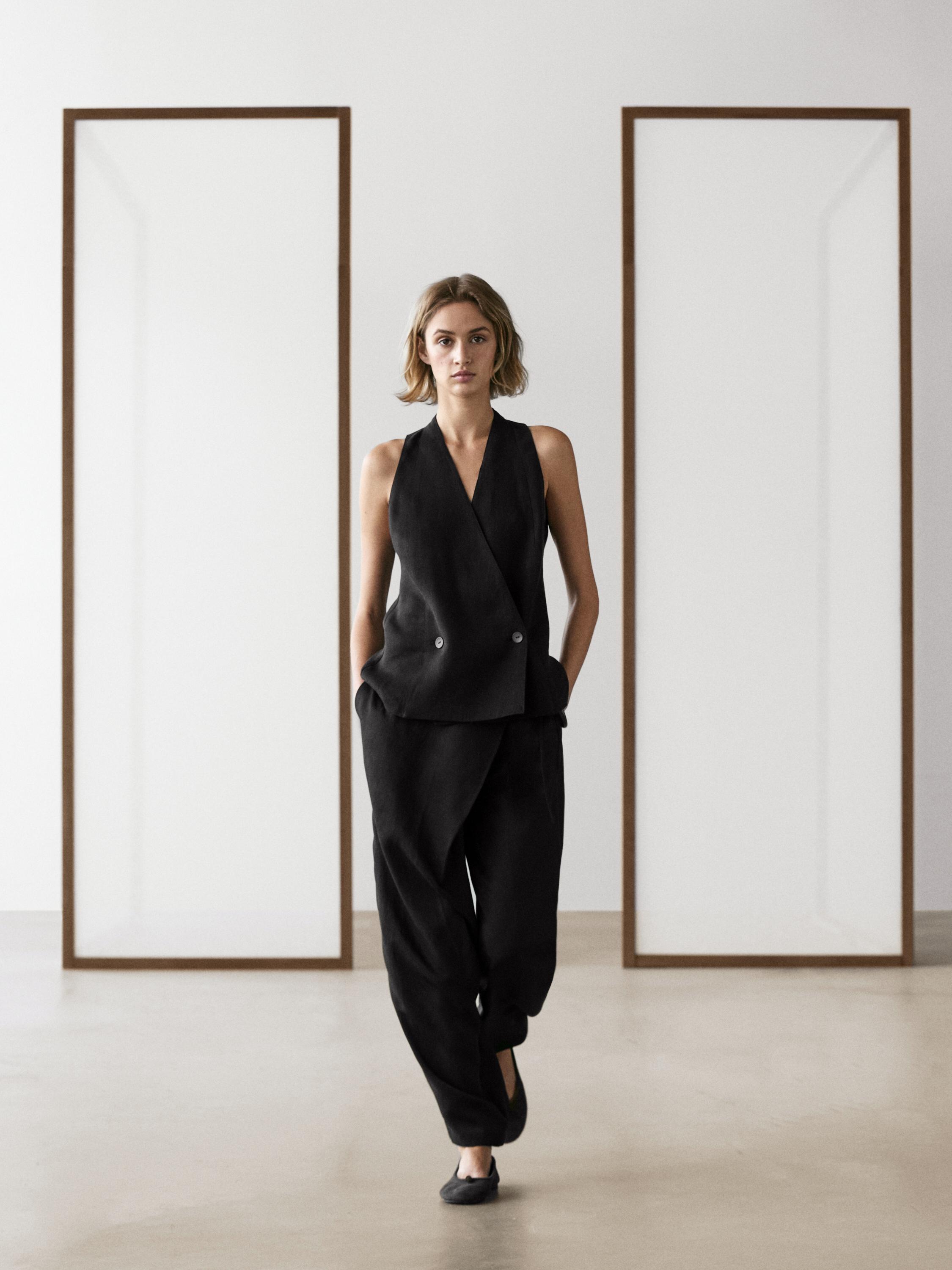 Black double-breasted vest and black flowy sarong pants set, both with side pockets.