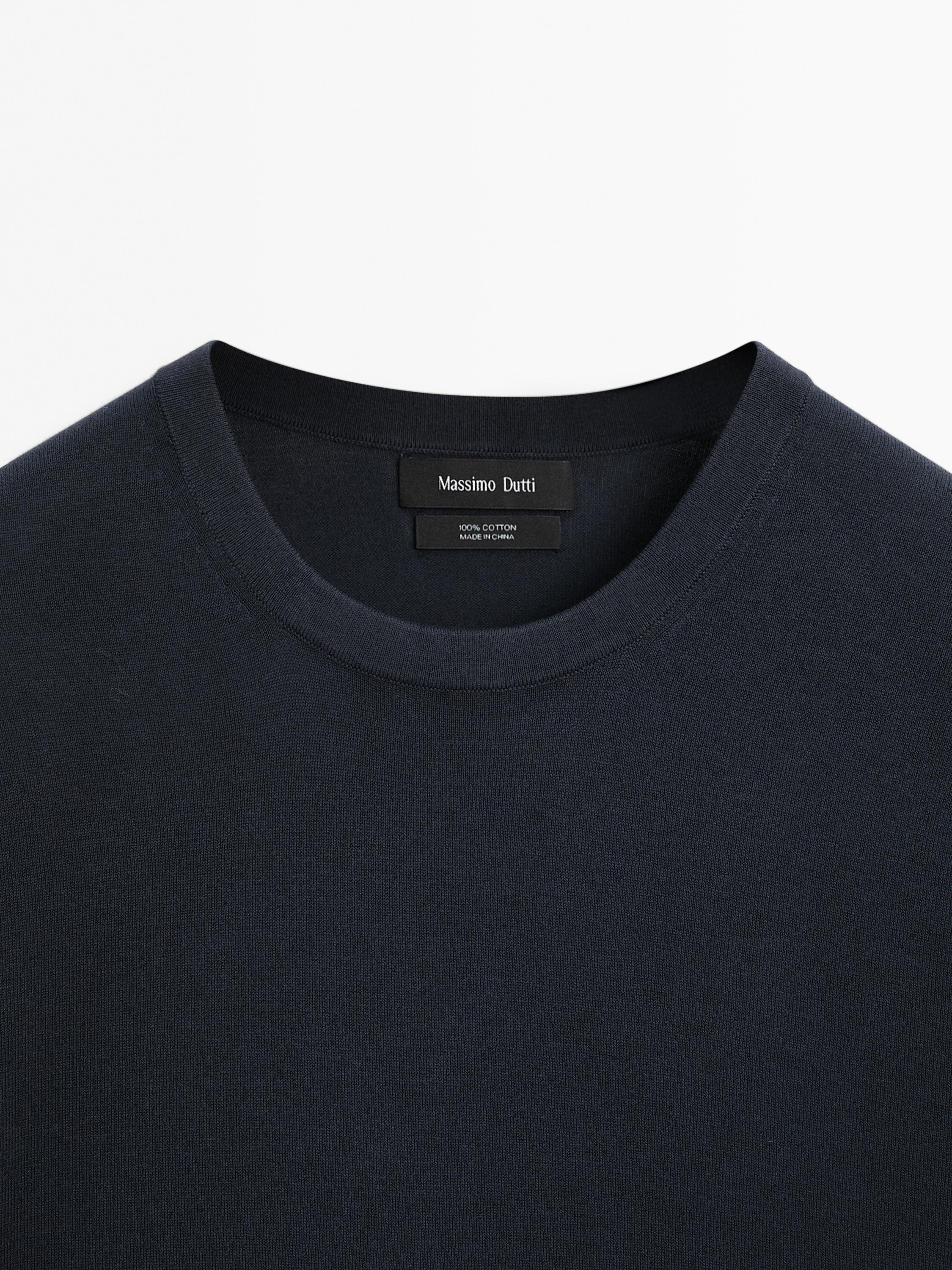 Pamje nga afër e jakës së rrumbullakët dhe etiketës së bluzës blu të errët