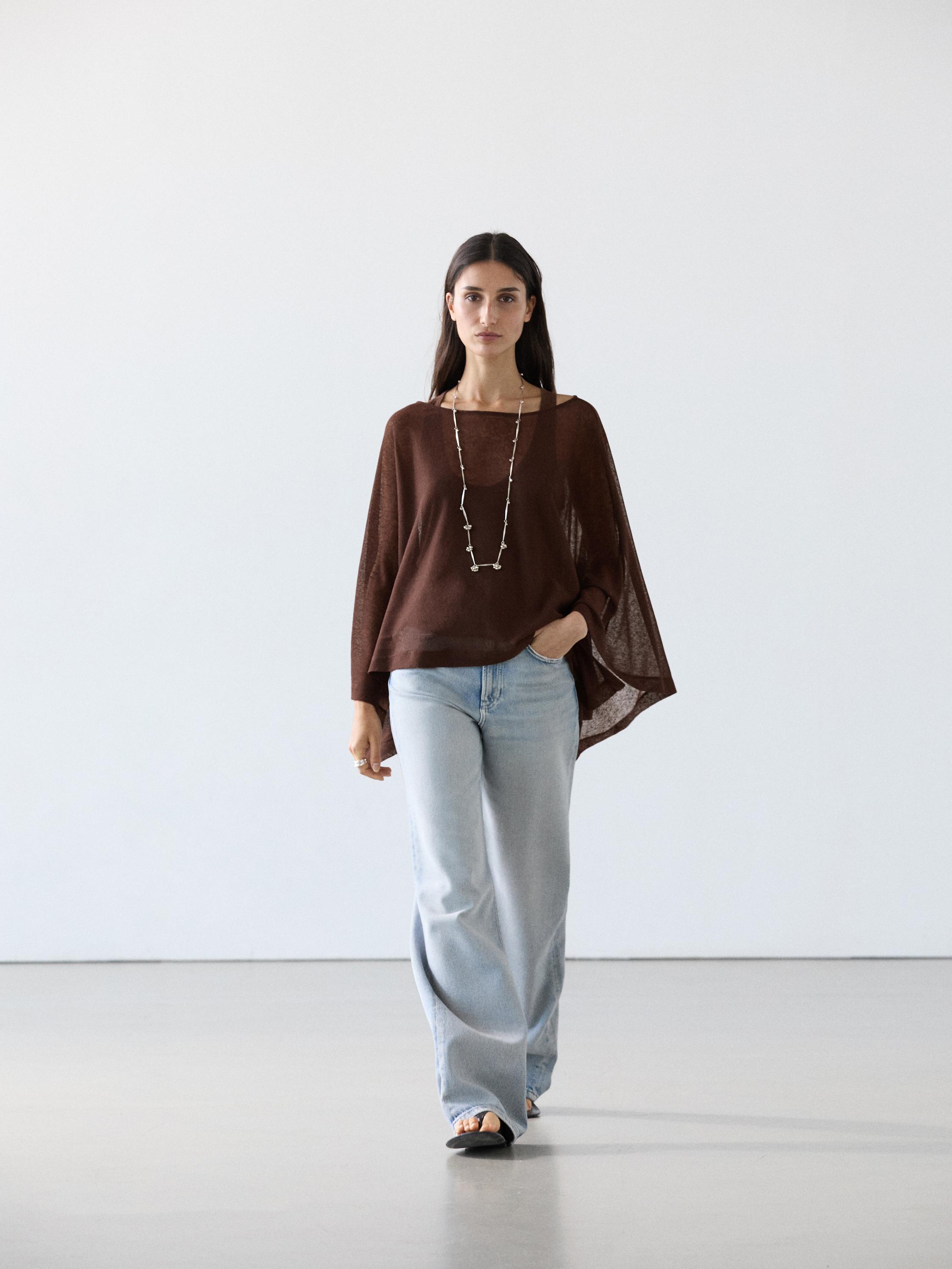 Conjunto de top castanho de manga comprida e jeans azul-claro de perna larga.