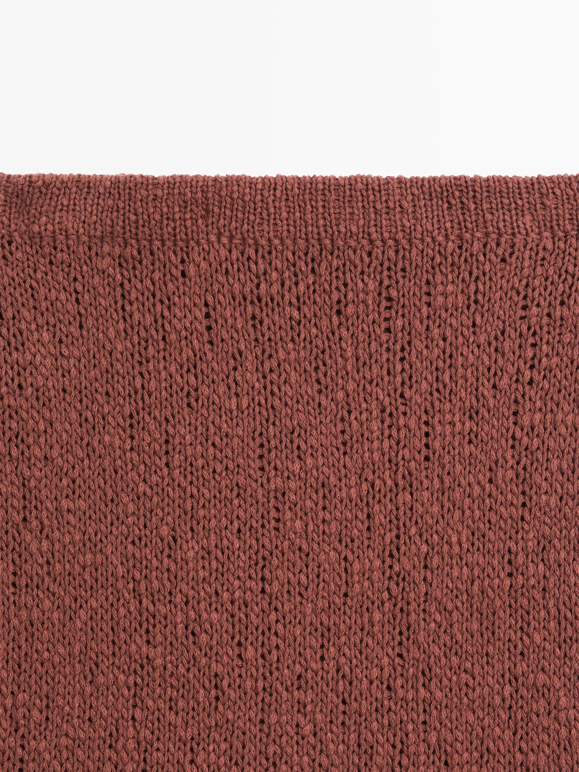 Détail de tissu tricot couleur tuile d'une jupe.