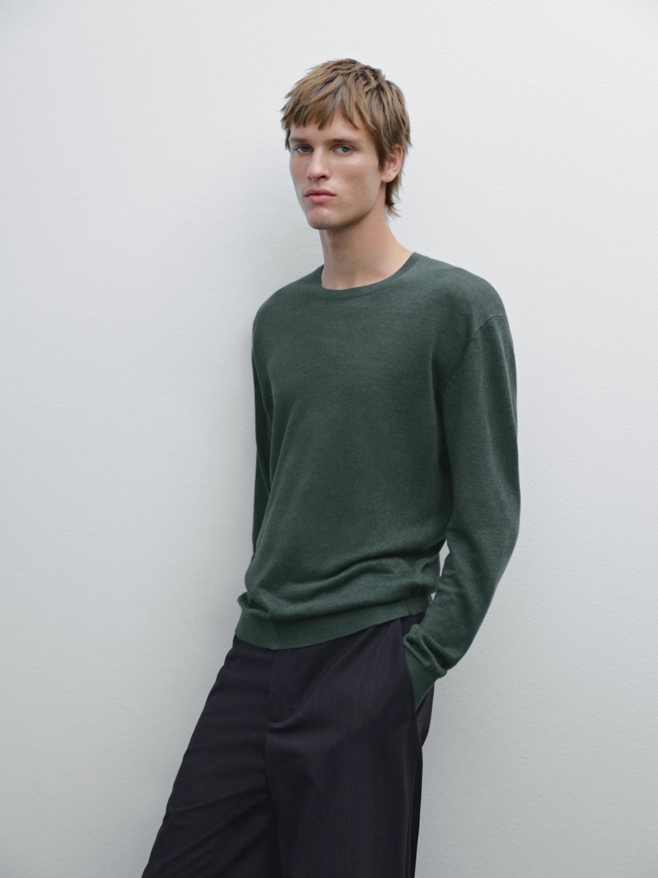 Ensemble pull vert foncé et pantalon foncé.