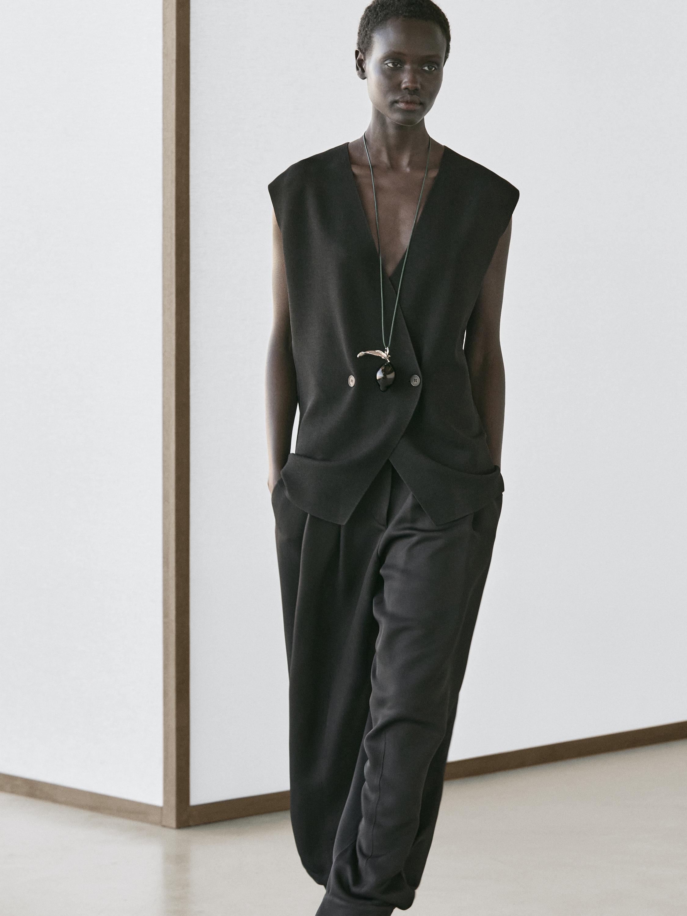 Black sleeveless button-up vest and loose black pants set.