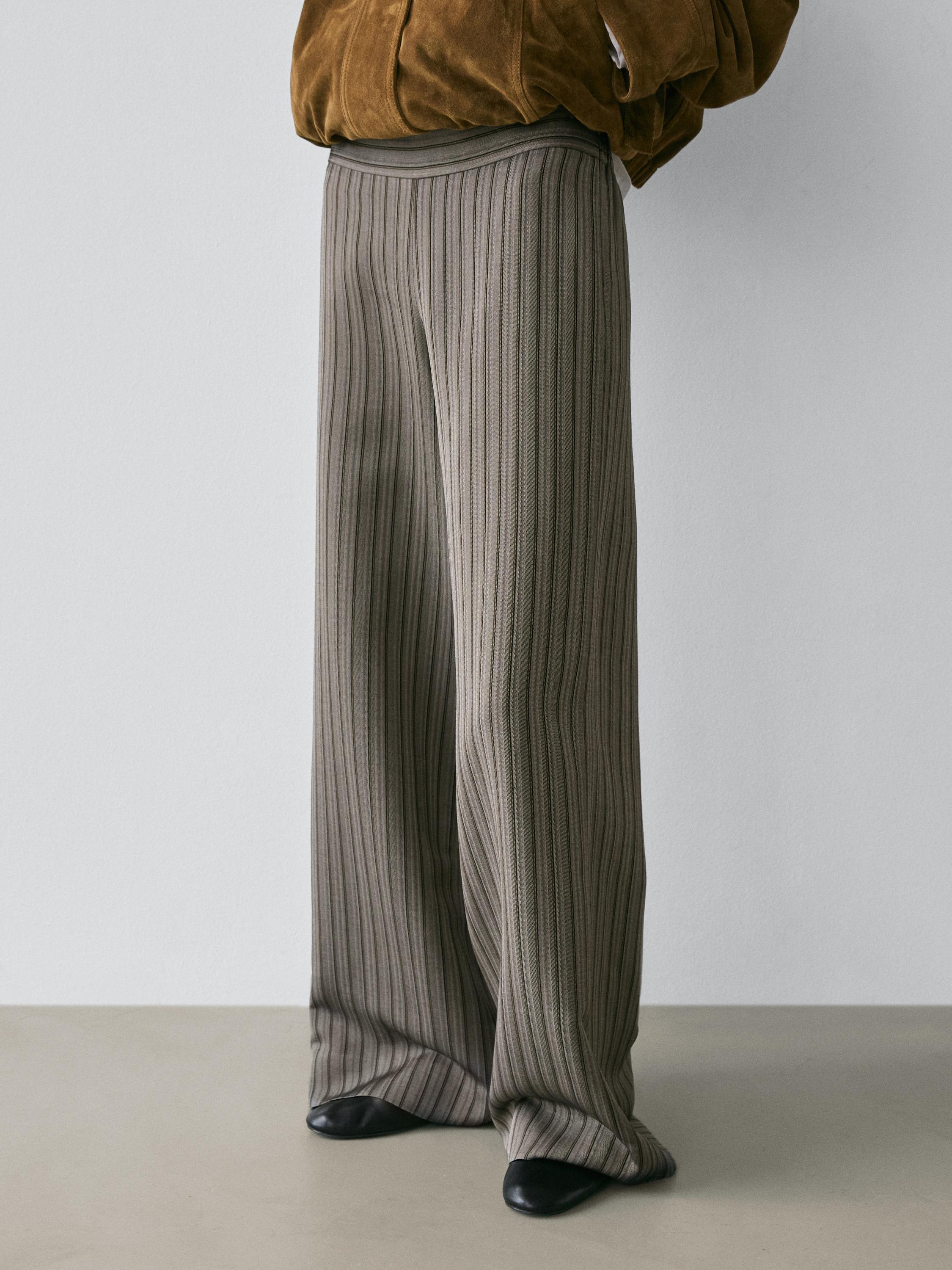 Plano medio de pantalón ancho gris con rayas verticales.