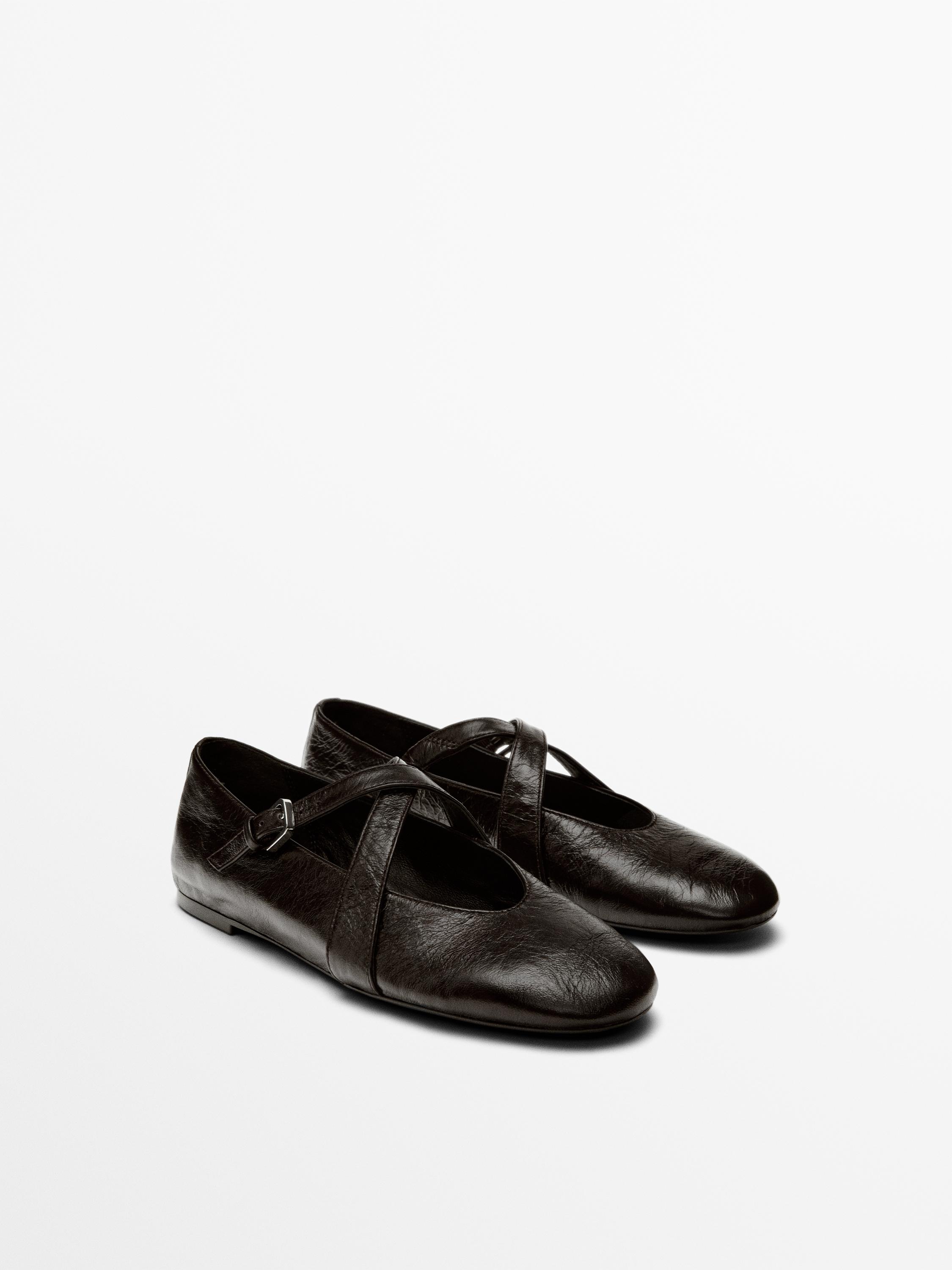 ภาพด้านหน้าของรองเท้าบัลเลต์สีน้ำตาลแบบมีสายไขว้และหัวเข็มขัด