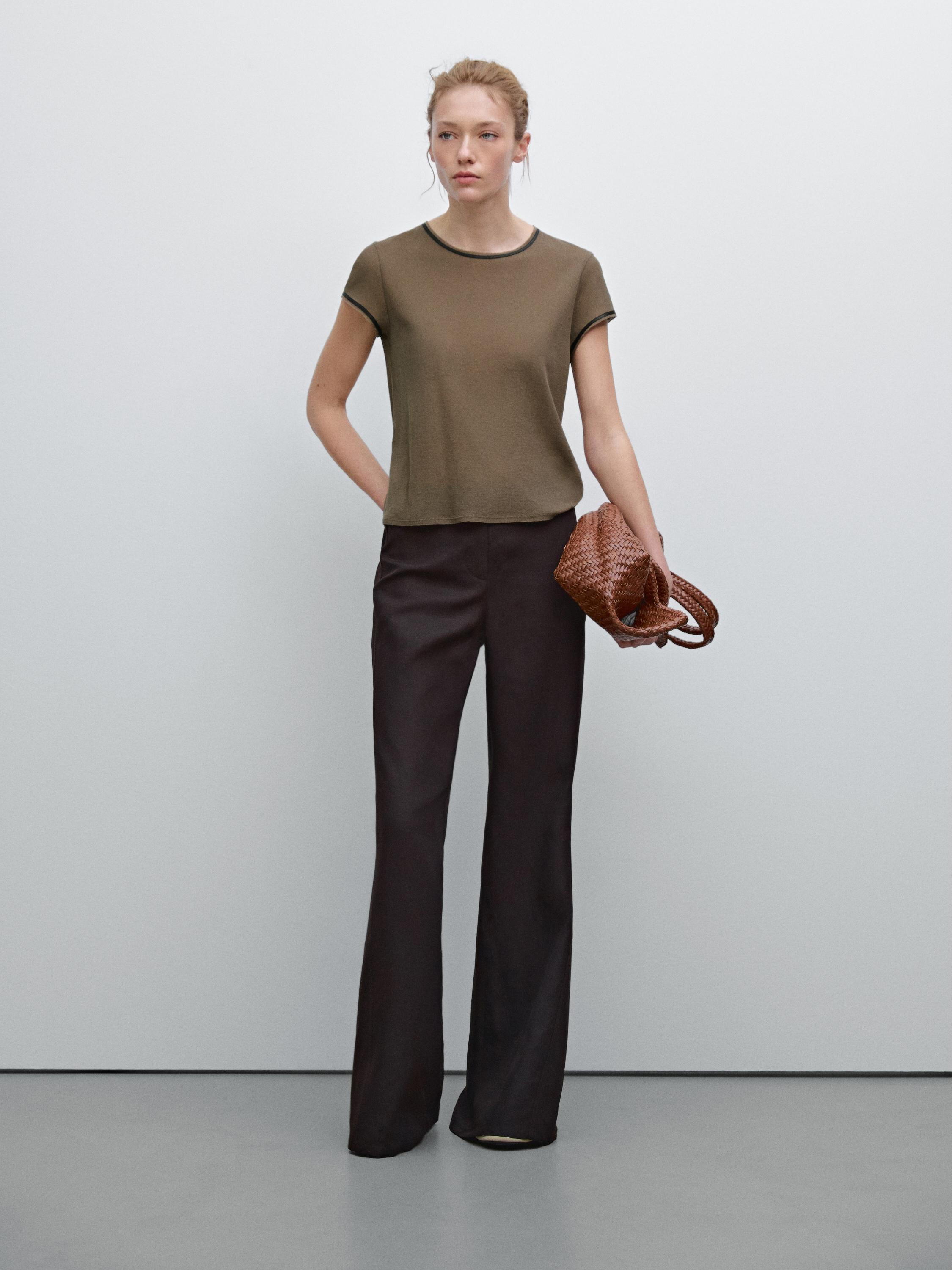 طقم يتكون من تي شيرت بني وبنطلون أسود واسع.