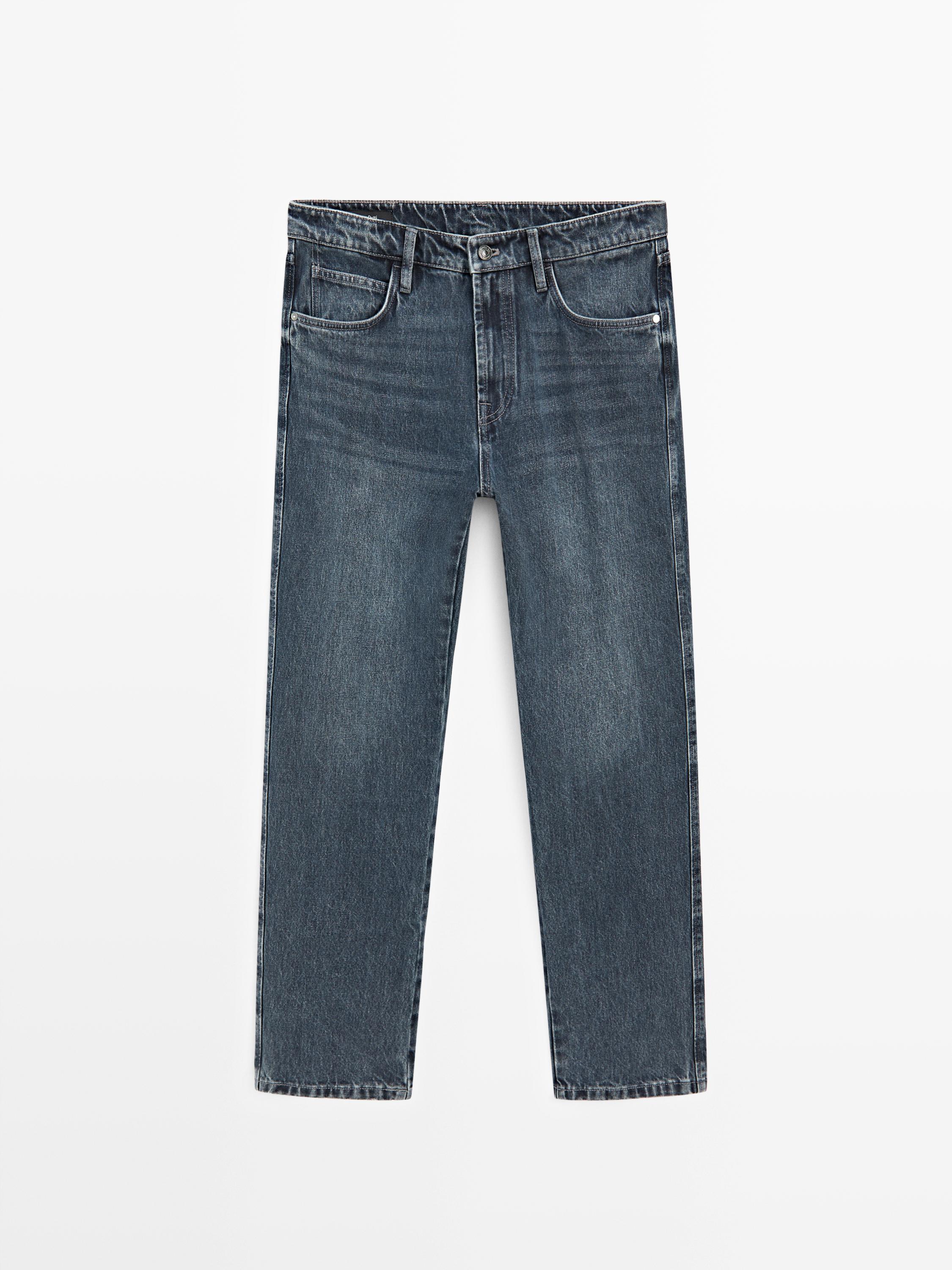 Vue de face d'un jean bleu tapered fit avec poches avant et arrière, fermeture boutonnée et zippée.