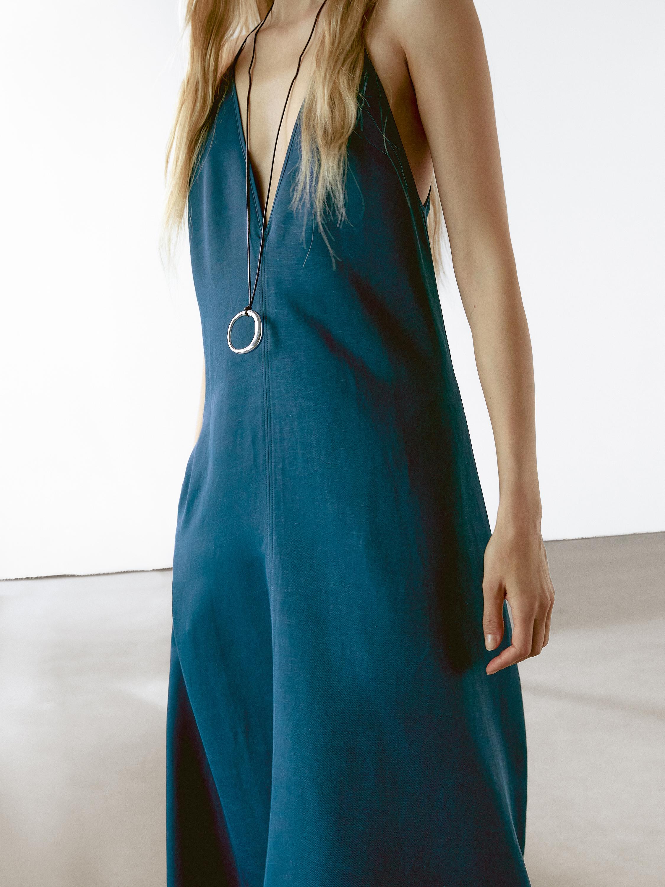 لقطة مقرّبة لفستان أزرق بدون أكمام بفتحة صدر واسعة وعقد طويل