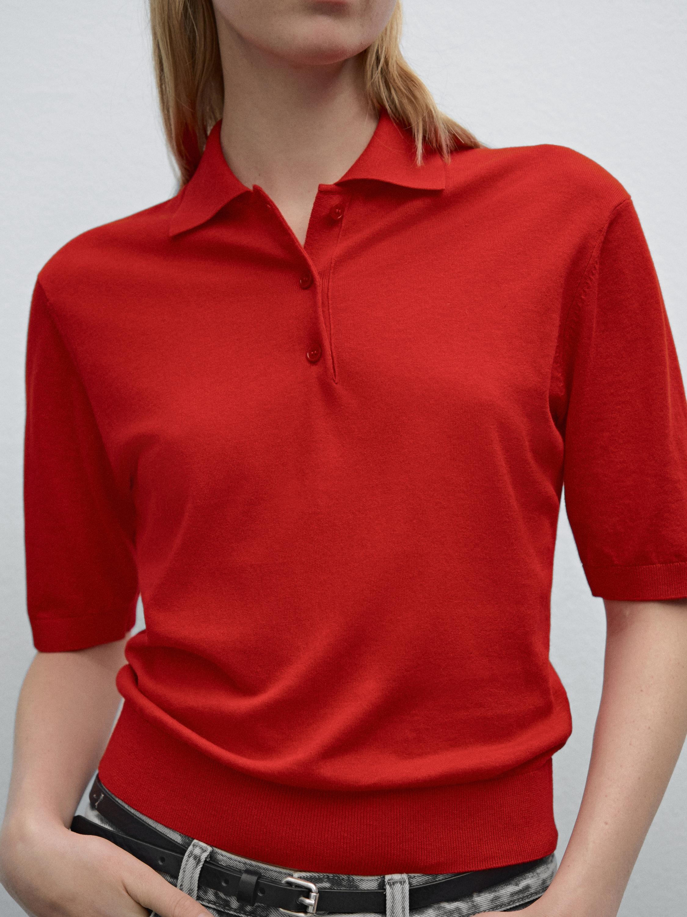 Plano medio de polo rojo con cuello y tres botones visibles.