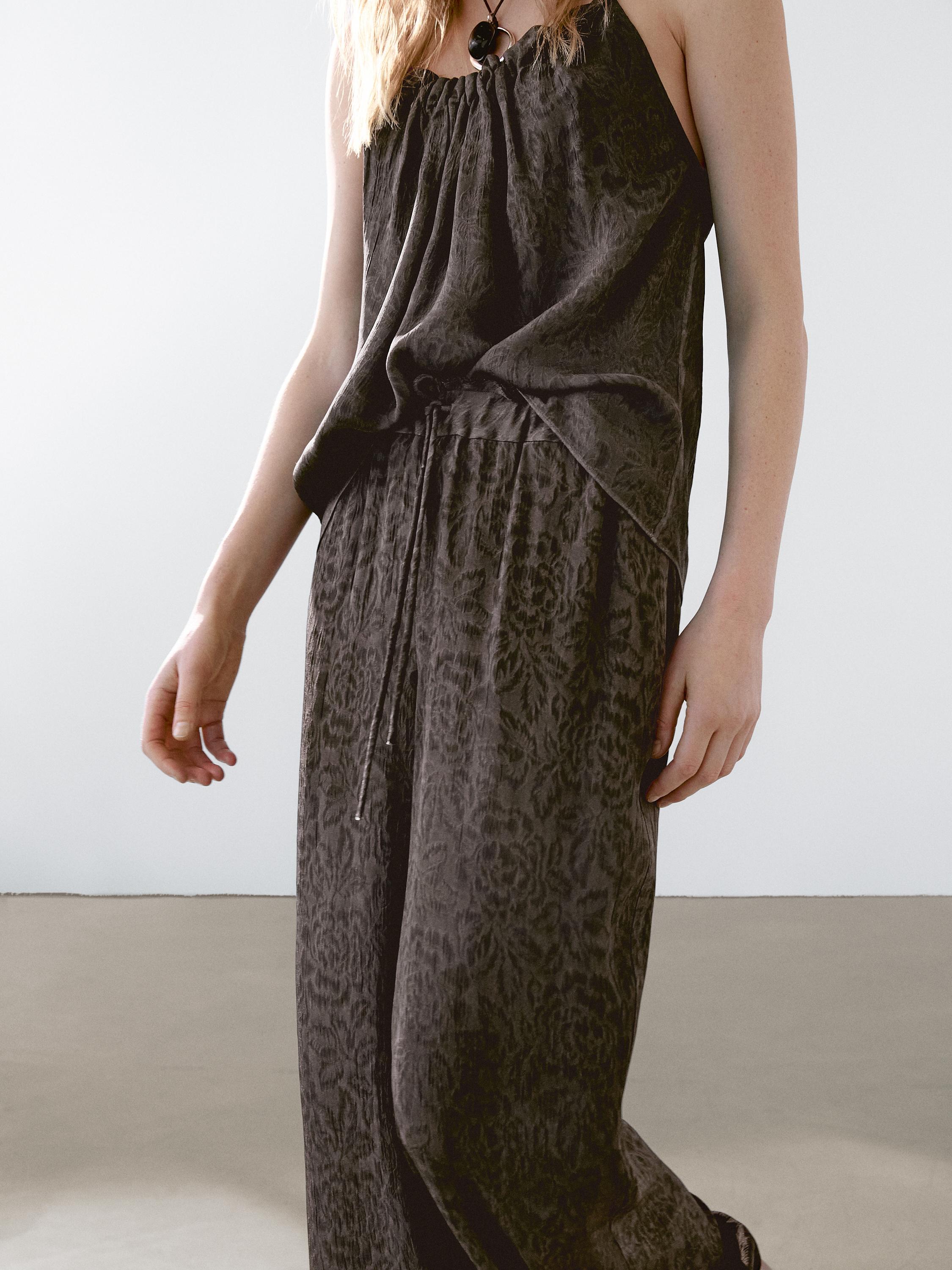 طقم مكون من توب بدون أكمام وبنطلون داكن اللون، بخصر عالٍ وقابل للتعديل.