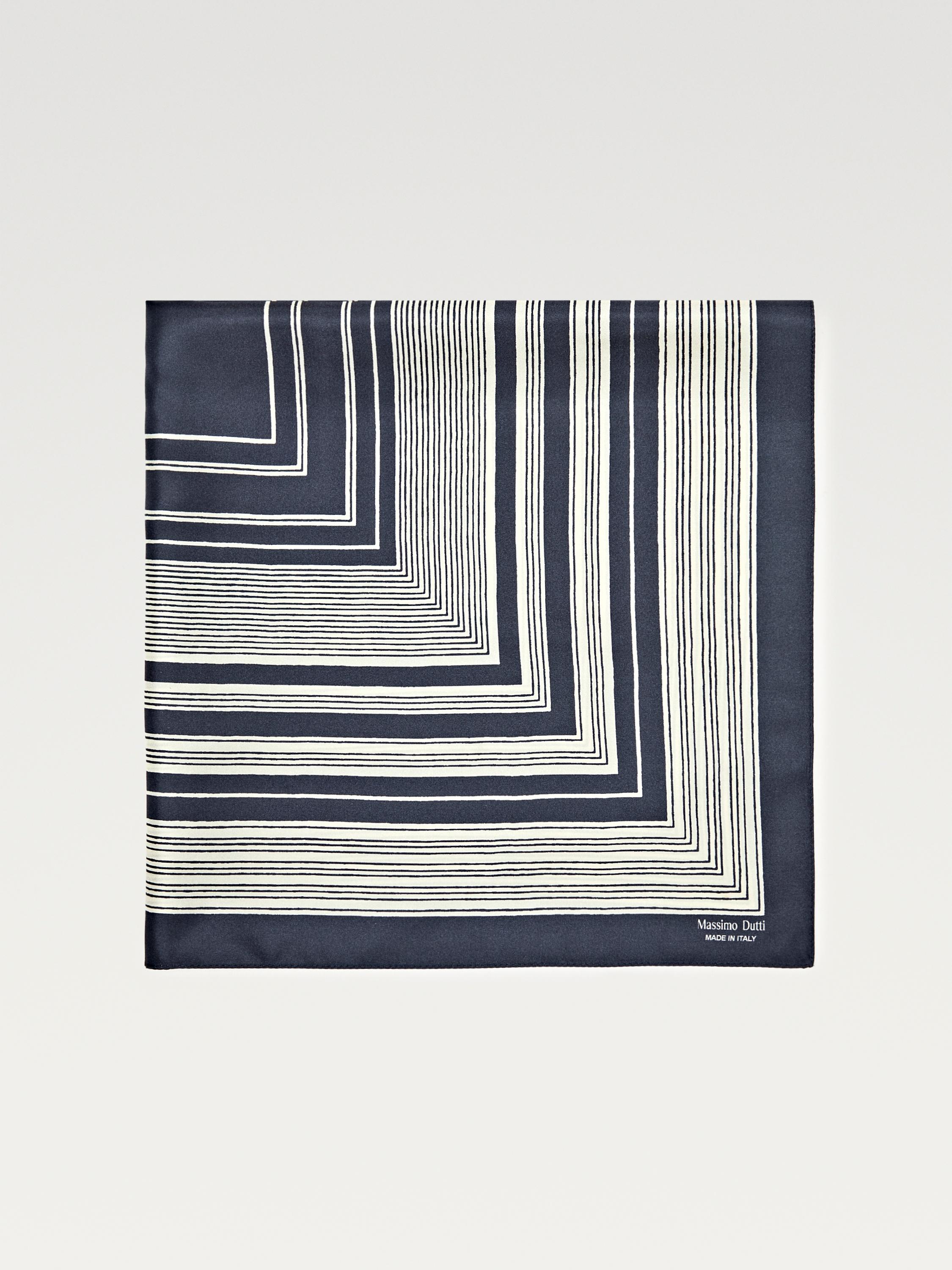 Vista frontal de pañuelo azul con líneas blancas en patrón geométrico. Texto visible: "Massimo Dutti HECHO EN ITALIA". Medidas: 60 x 60 cm.