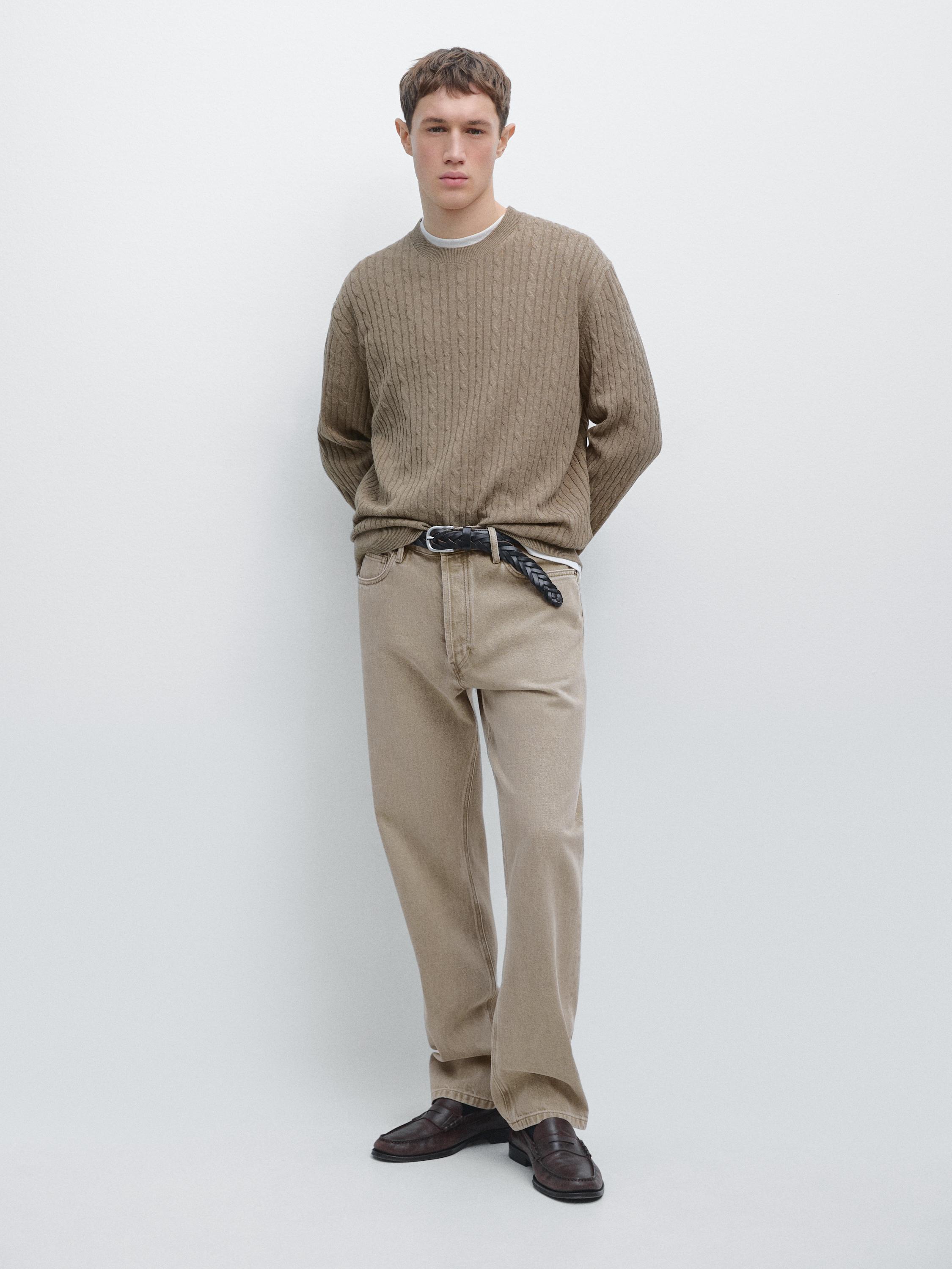 Ensemble de pull kaki clair en maille torsadée et pantalon beige avec ceinture noire.