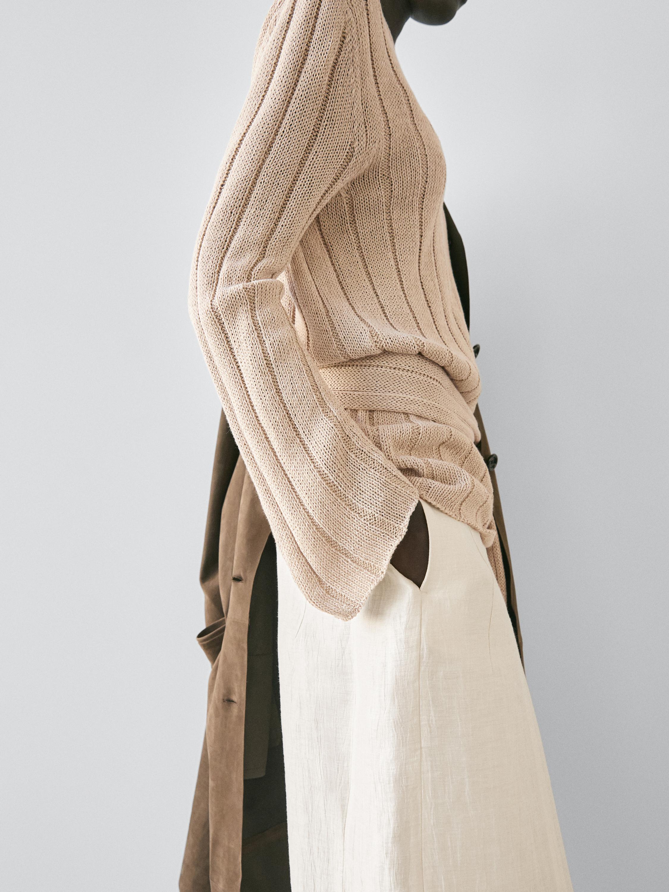 Plano medio de xersei beis de punto con mangas longas e pantalón bombacho beis con petos laterais.