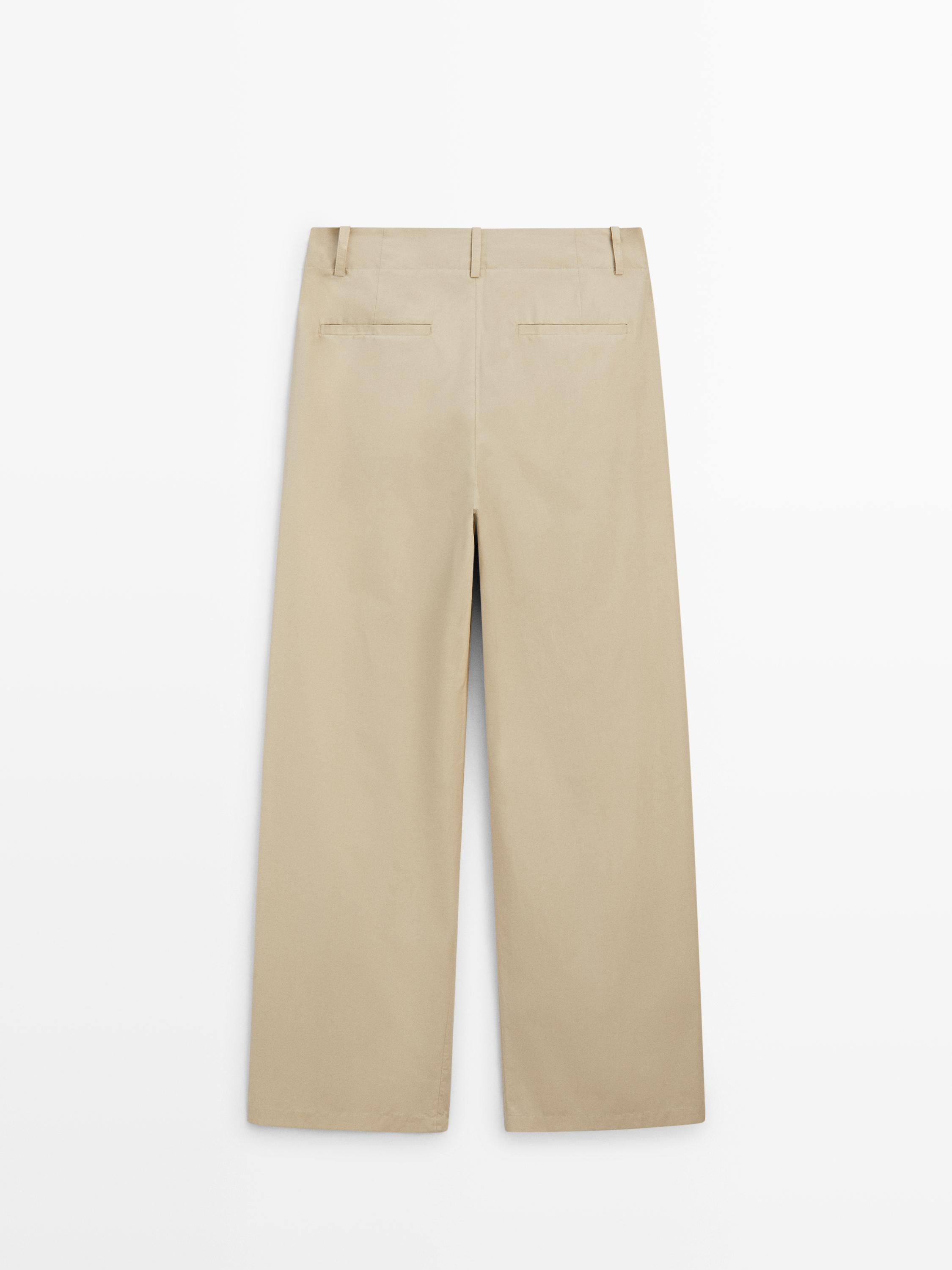 Arka cepleri olan kum rengi wide leg pantolonun arkadan görünümü.