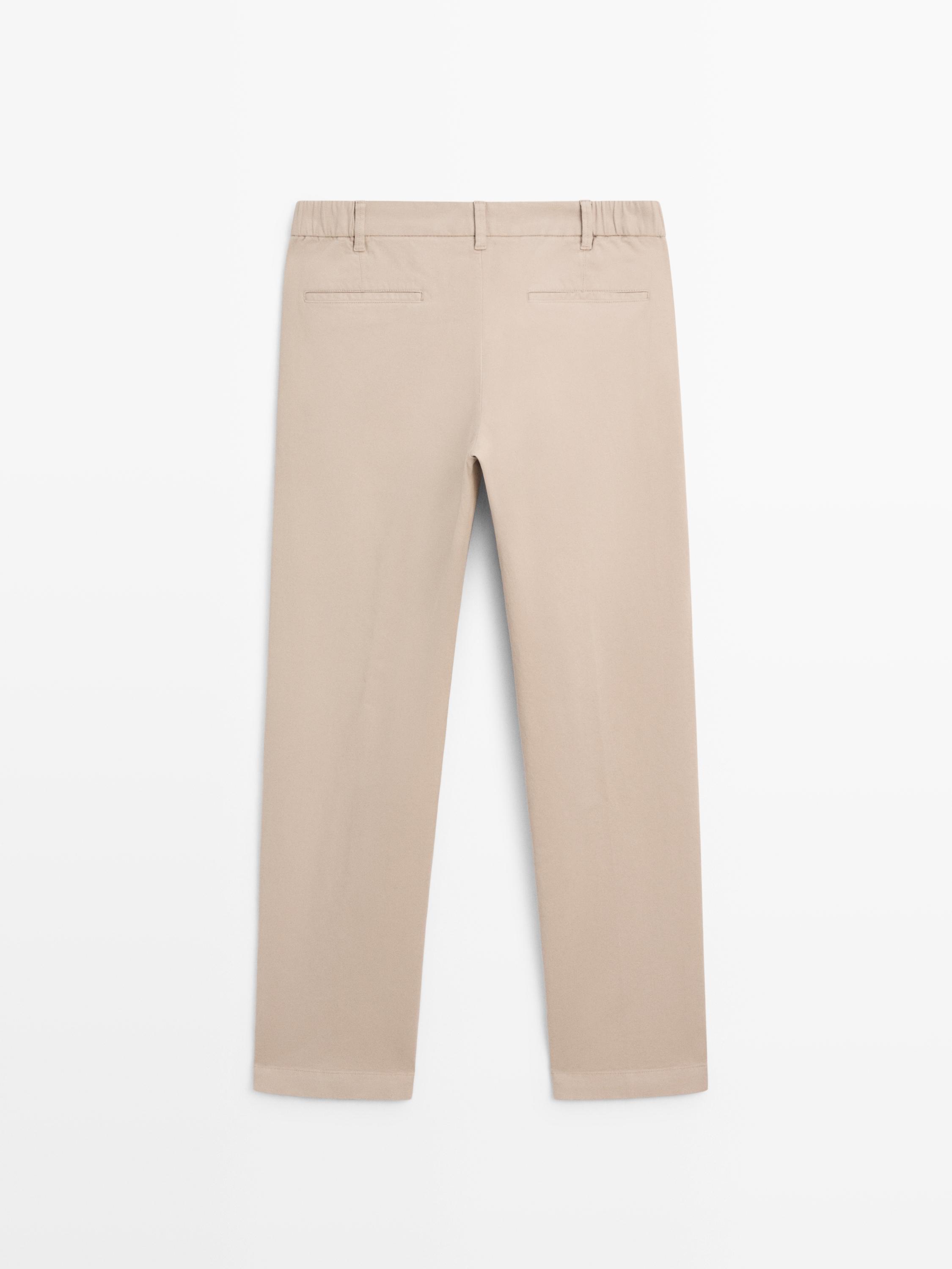 มุมมองด้านหลังของกางเกงขายาวทรงสลิมฟิตสีเบจพร้อมกระเป๋าหลัง