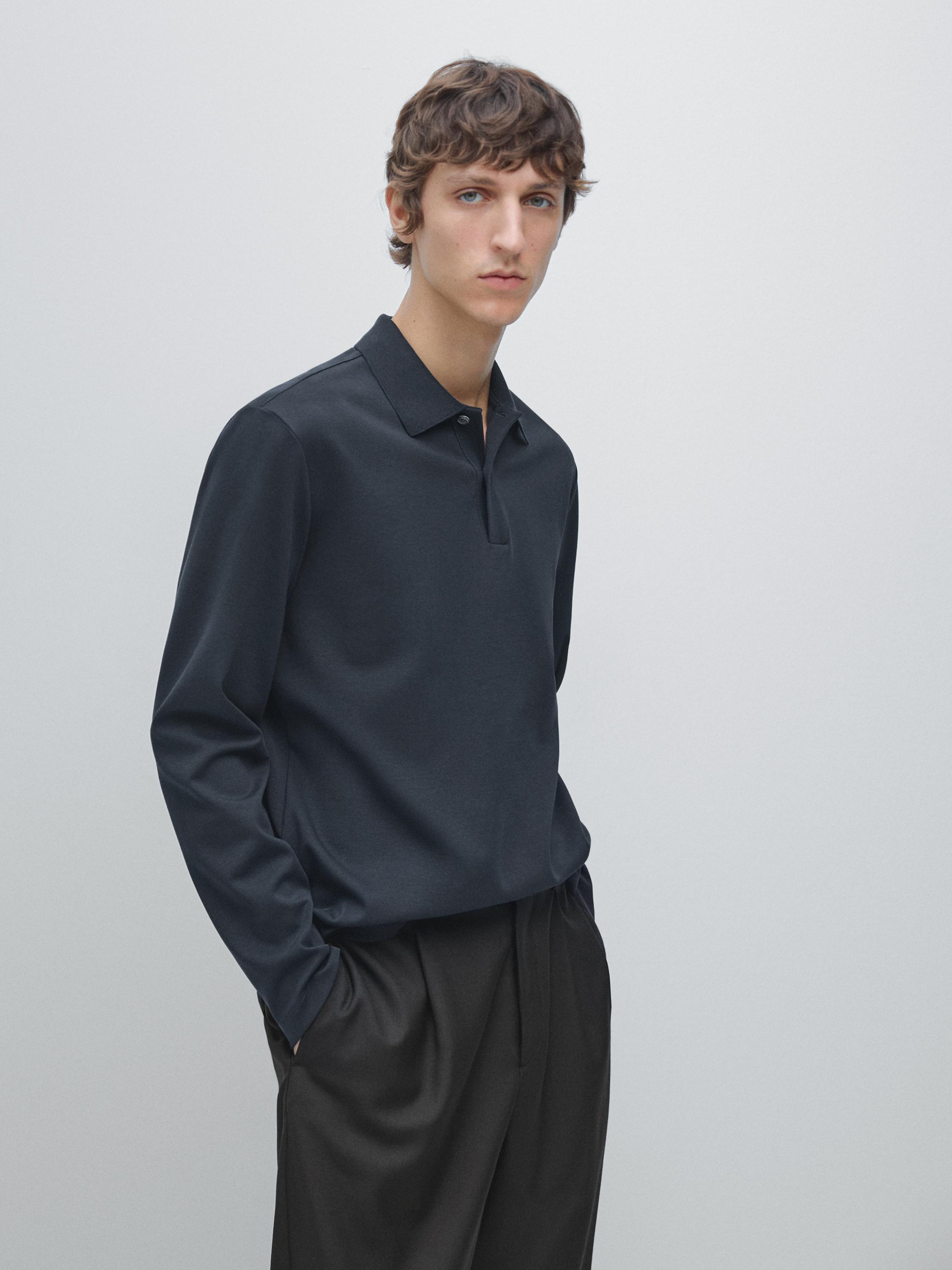 Marineblauwe polopak met lange mouwen, klassieke kraag en zwarte broek met plooien.