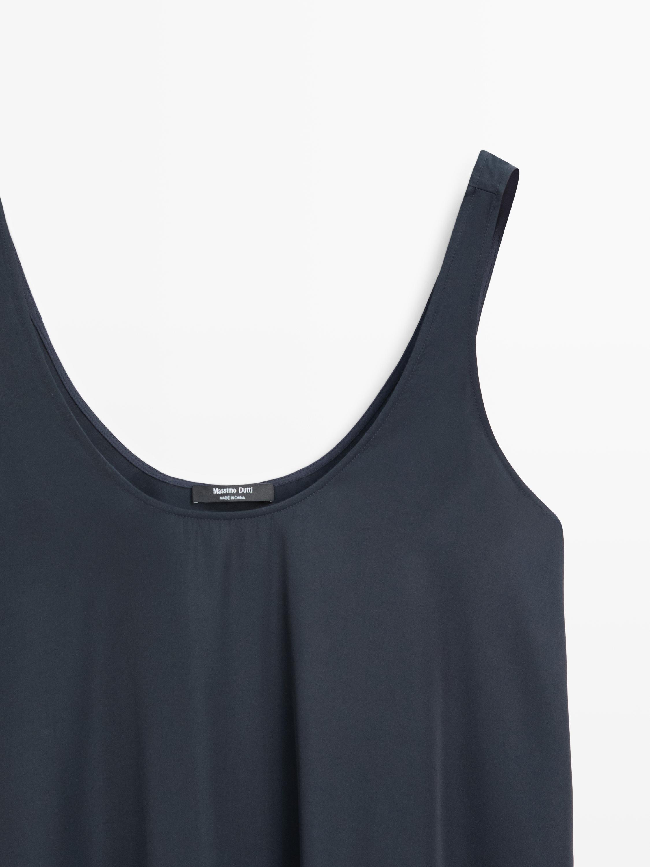 "Detail des Oberteils eines blauen Kleides mit Trägern und Rundhalsausschnitt."