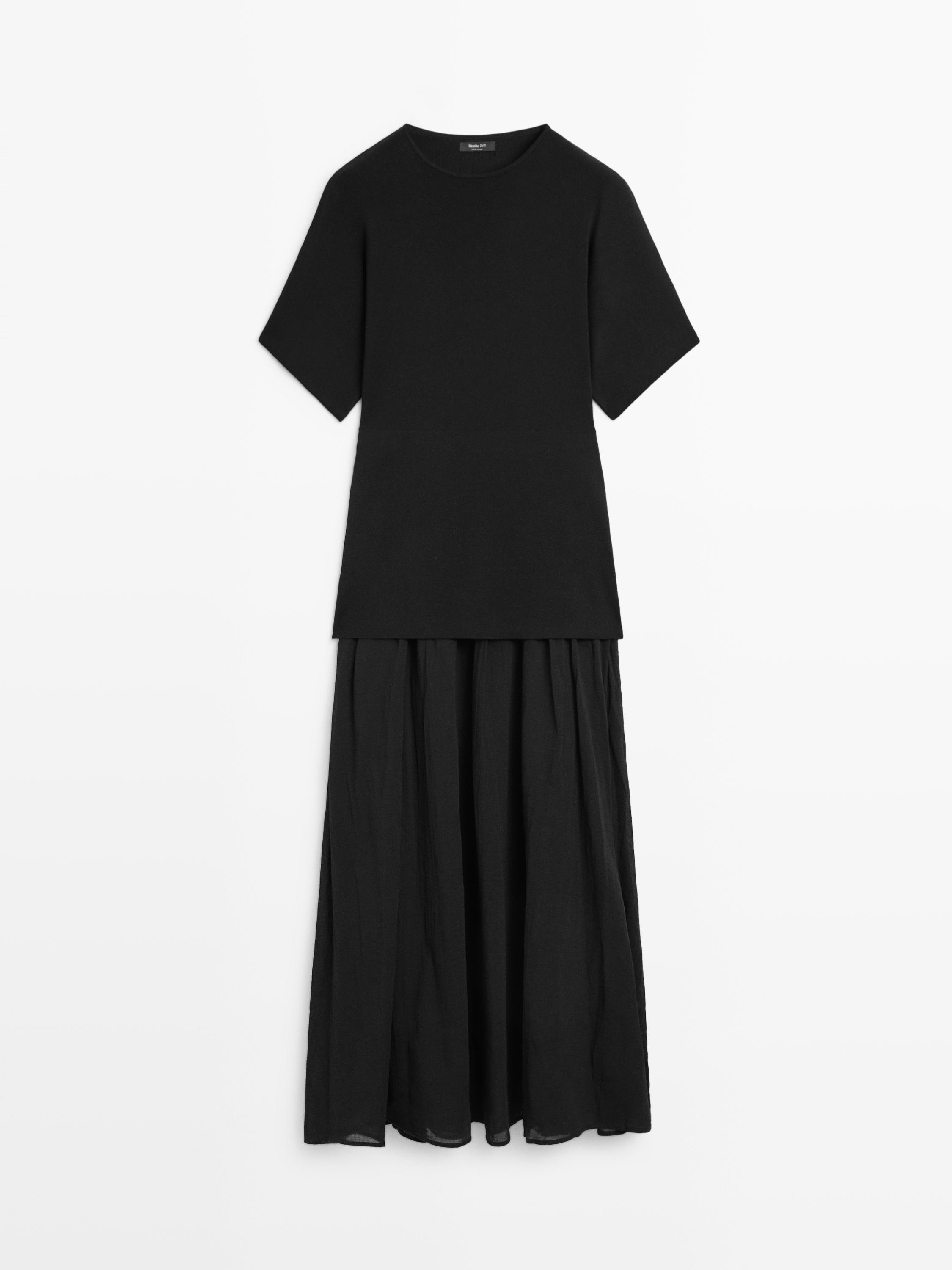 Vue de face d'une robe midi noire, à manches courtes, avec un haut ajusté et une jupe ample plissée.