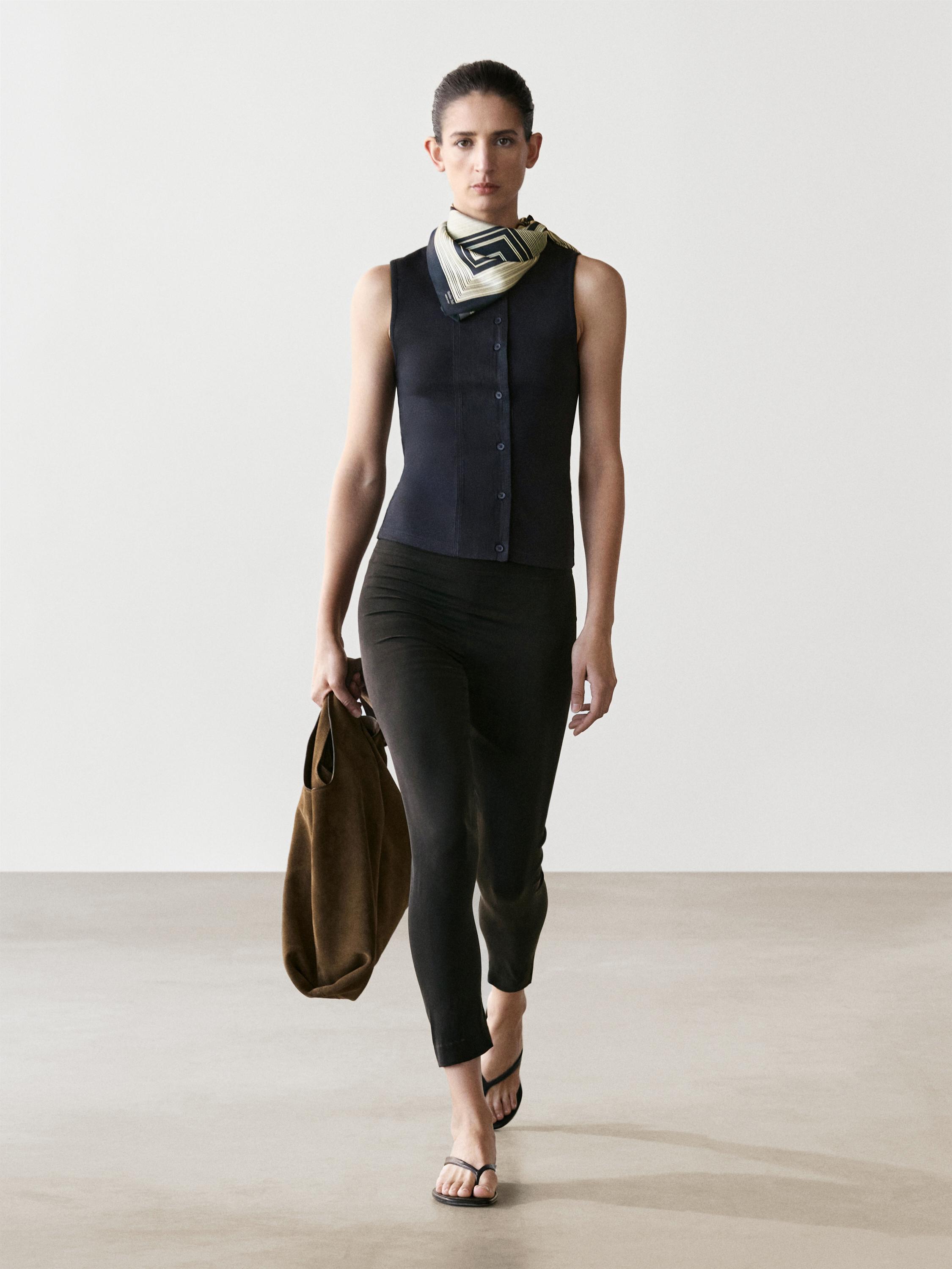 Σετ μπλουζάκι αμάνικο ναυτικό μπλε με κουμπιά, στενό μαύρο παντελόνι, εμπριμέ φουλάρι και καφέ τσάντα.