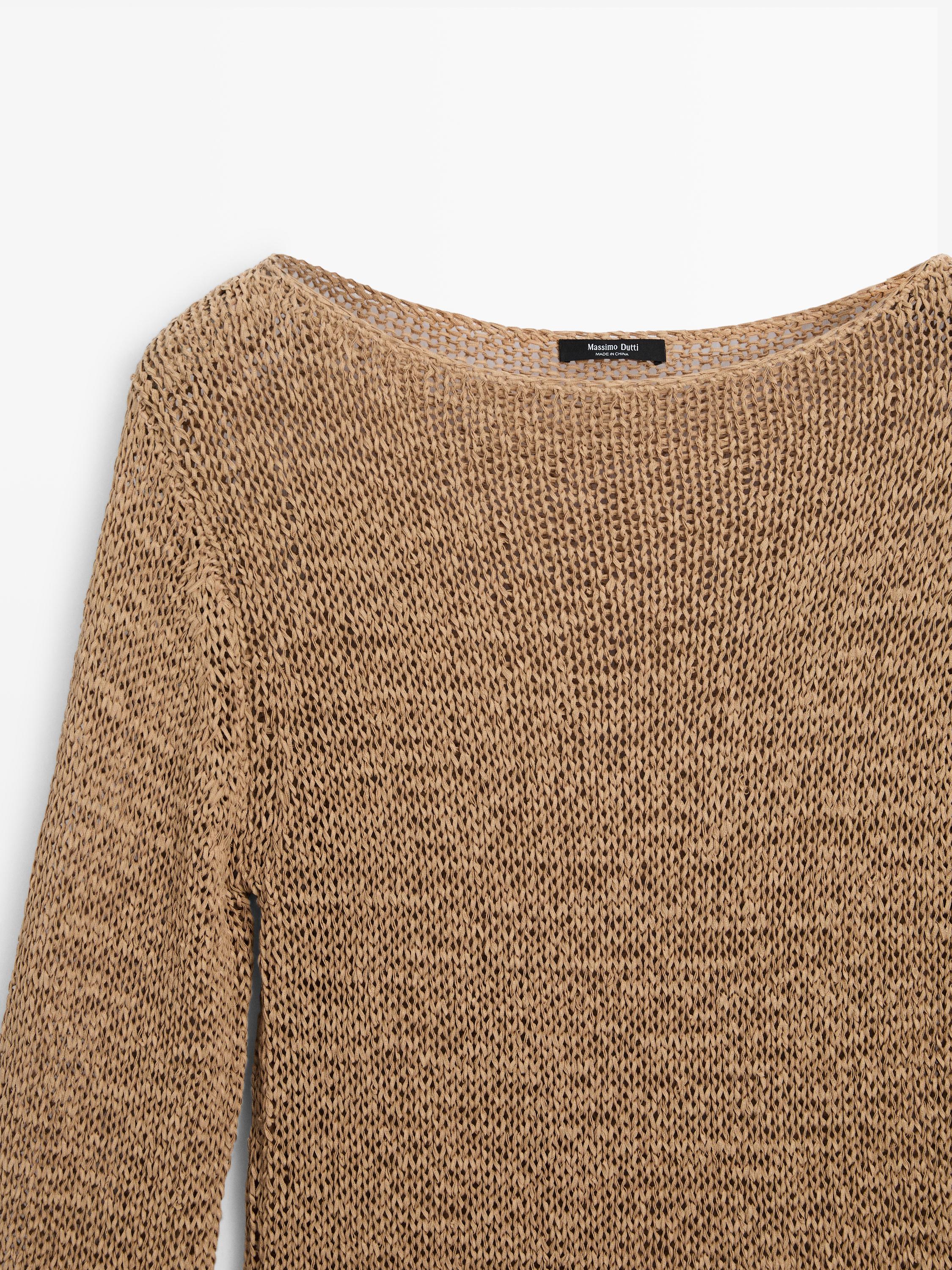 Plano medio de suéter tostado de punto con cuello barco, detalle de etiqueta visible en el interior del cuello.